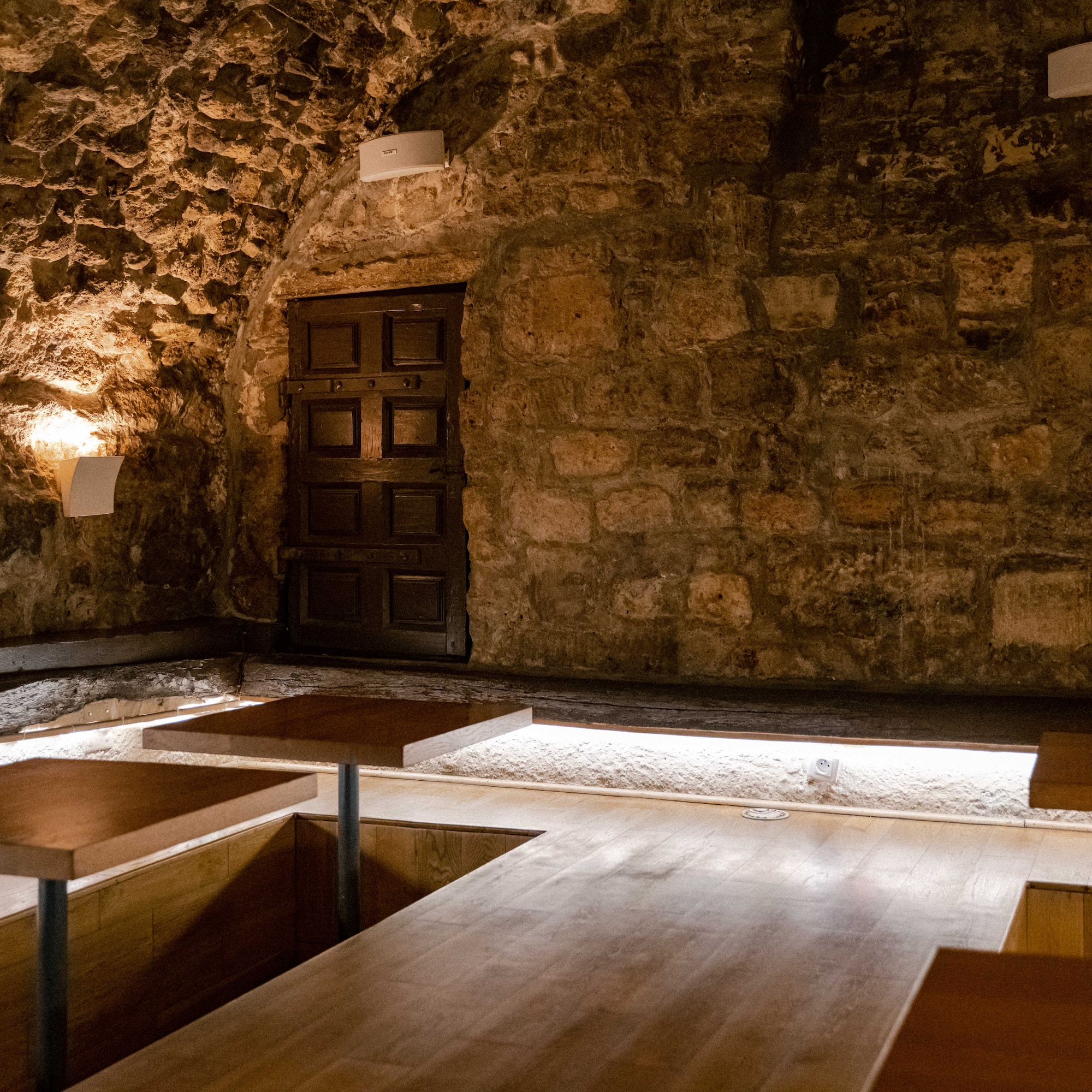 a room with a stone wall and wooden tables