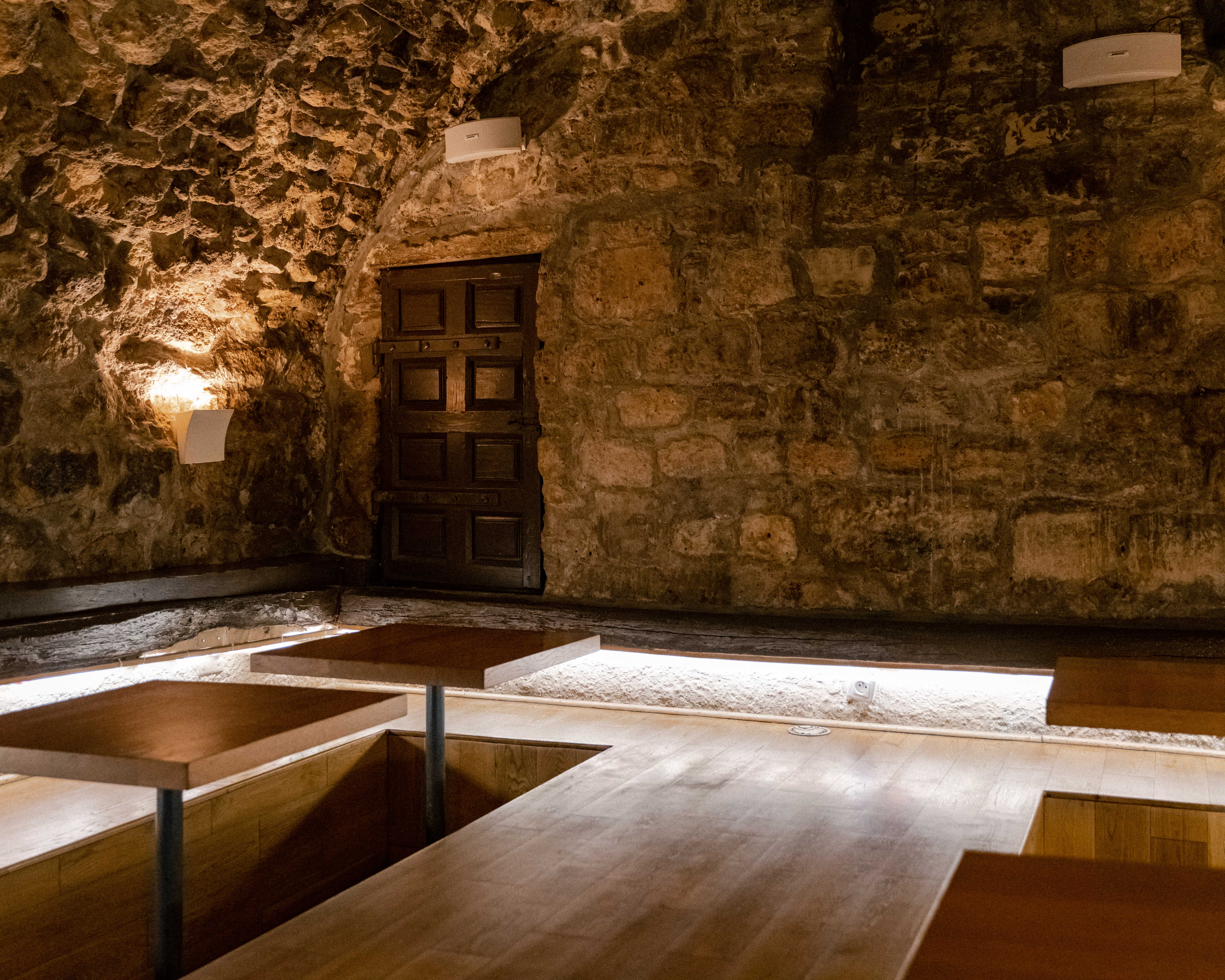 a room with a stone wall and wooden tables