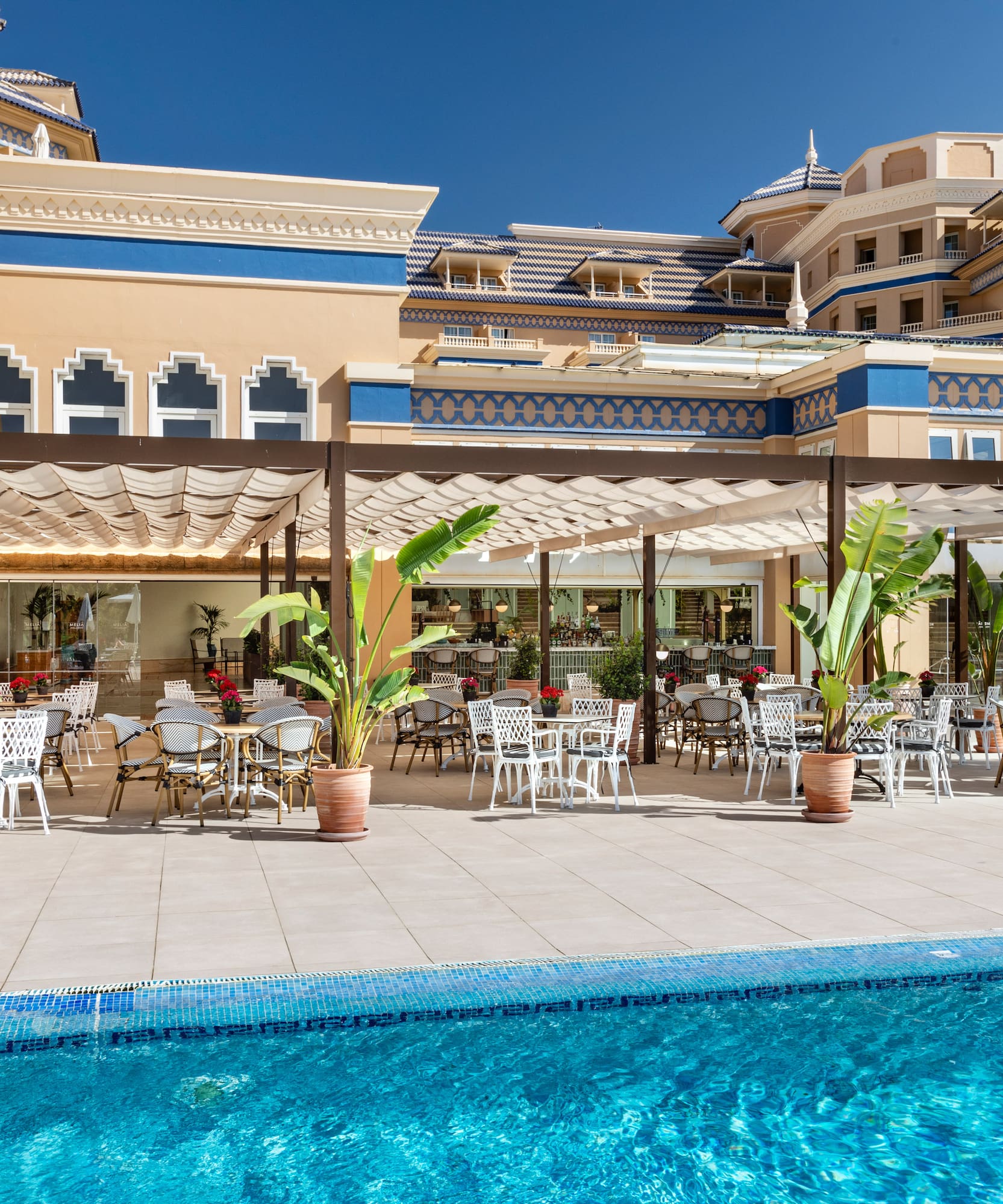 a pool with tables and chairs in front of a building