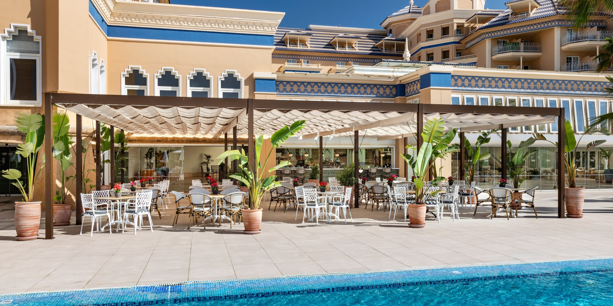a pool with tables and chairs in front of a building