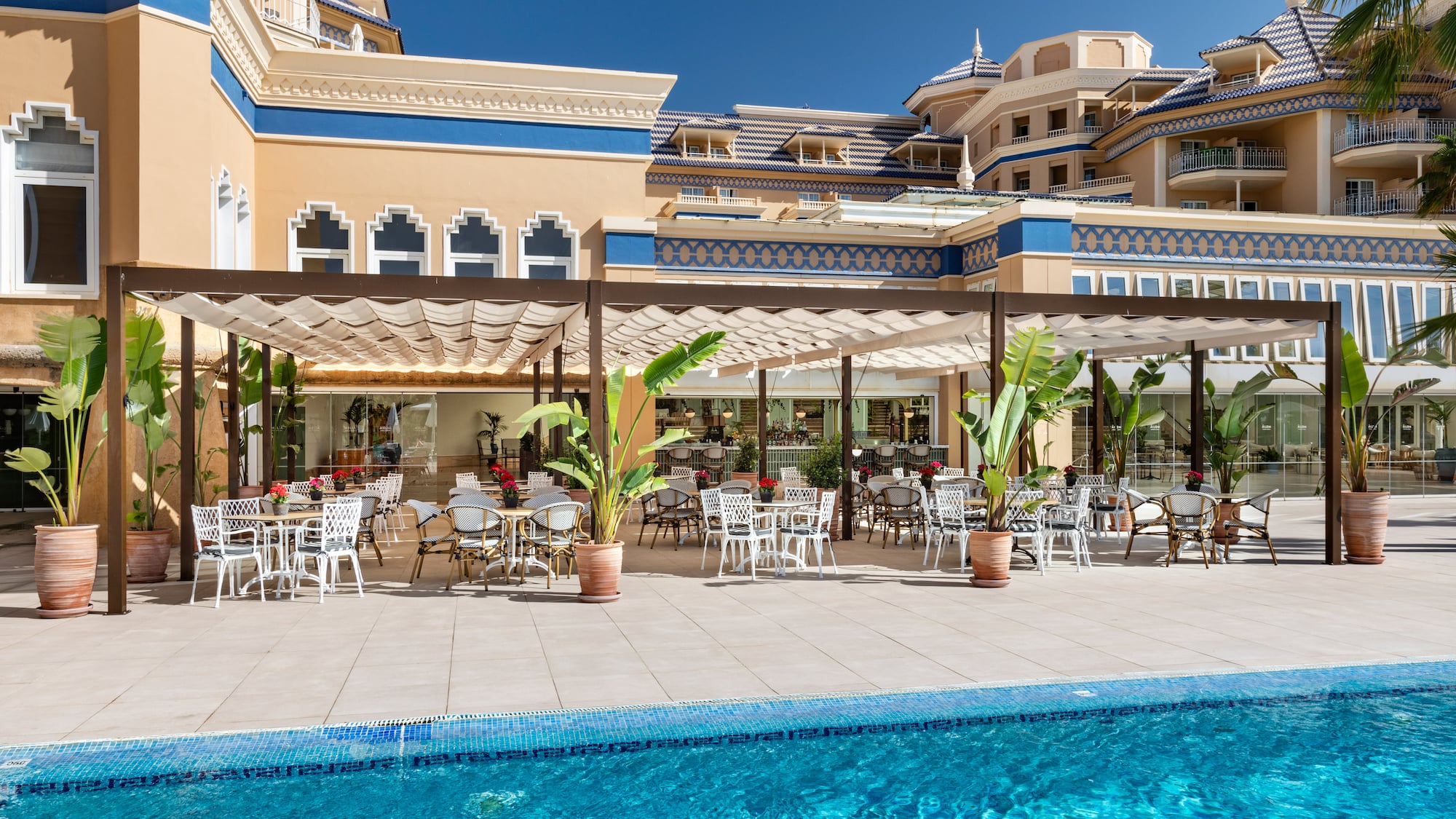 a pool with tables and chairs in front of a building