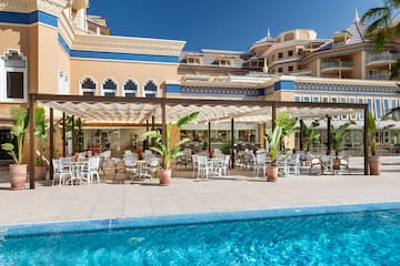 a pool with tables and chairs in front of a building