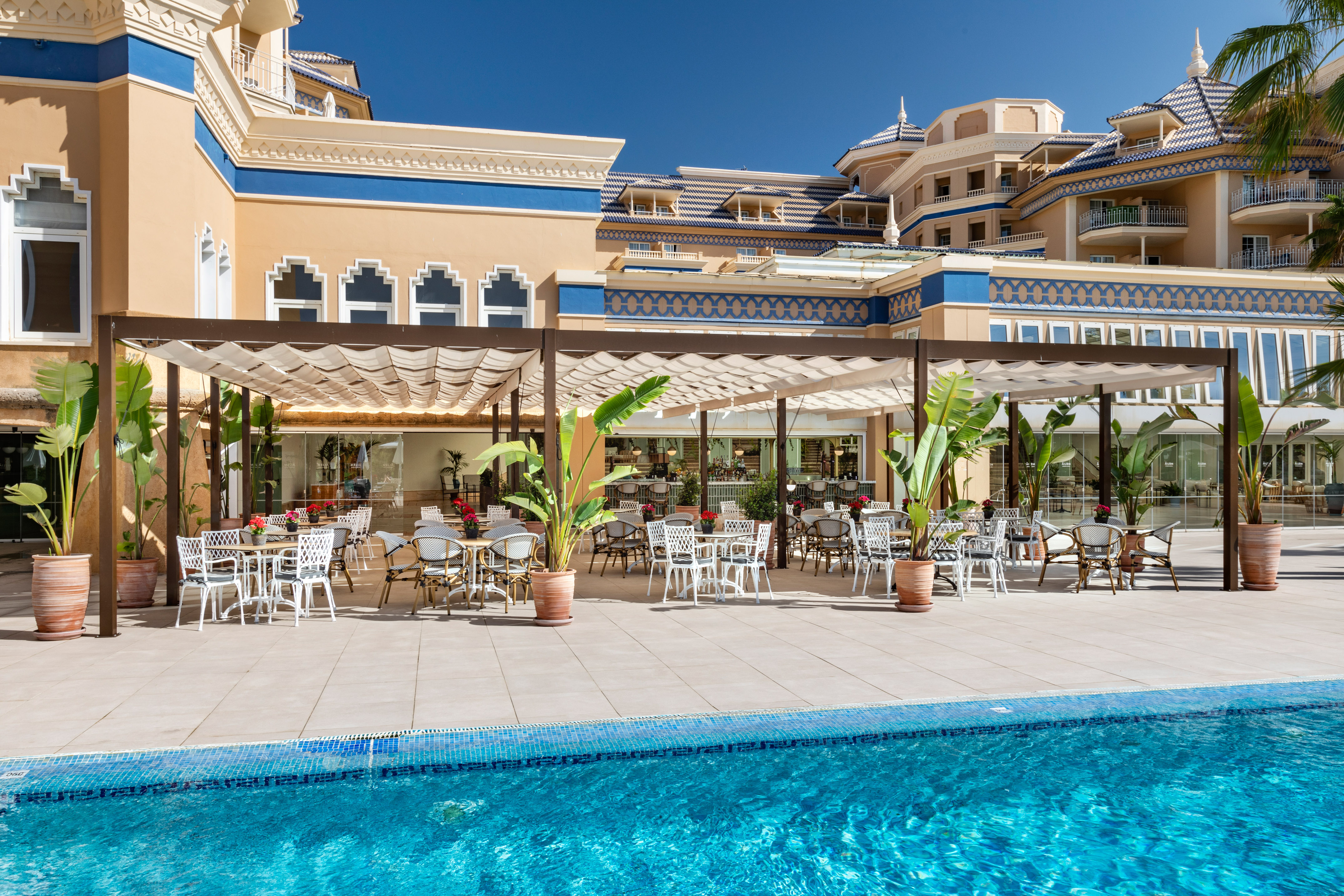 a pool with tables and chairs in front of a building