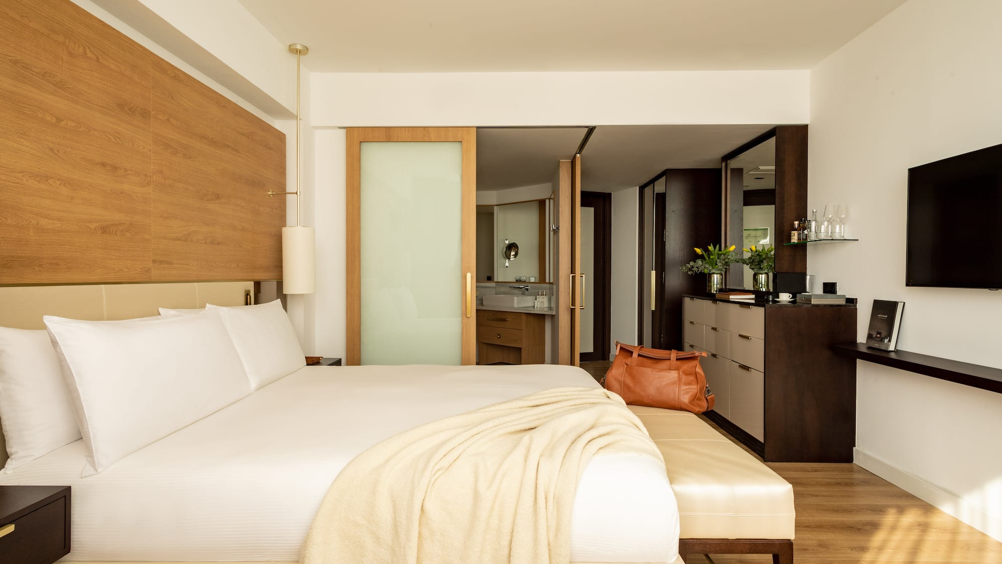 a bed with a white blanket and a brown bag in a room