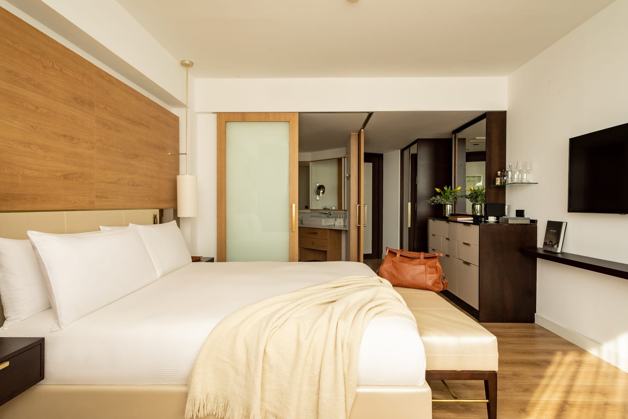 a bed with a white blanket and a brown bag in a room