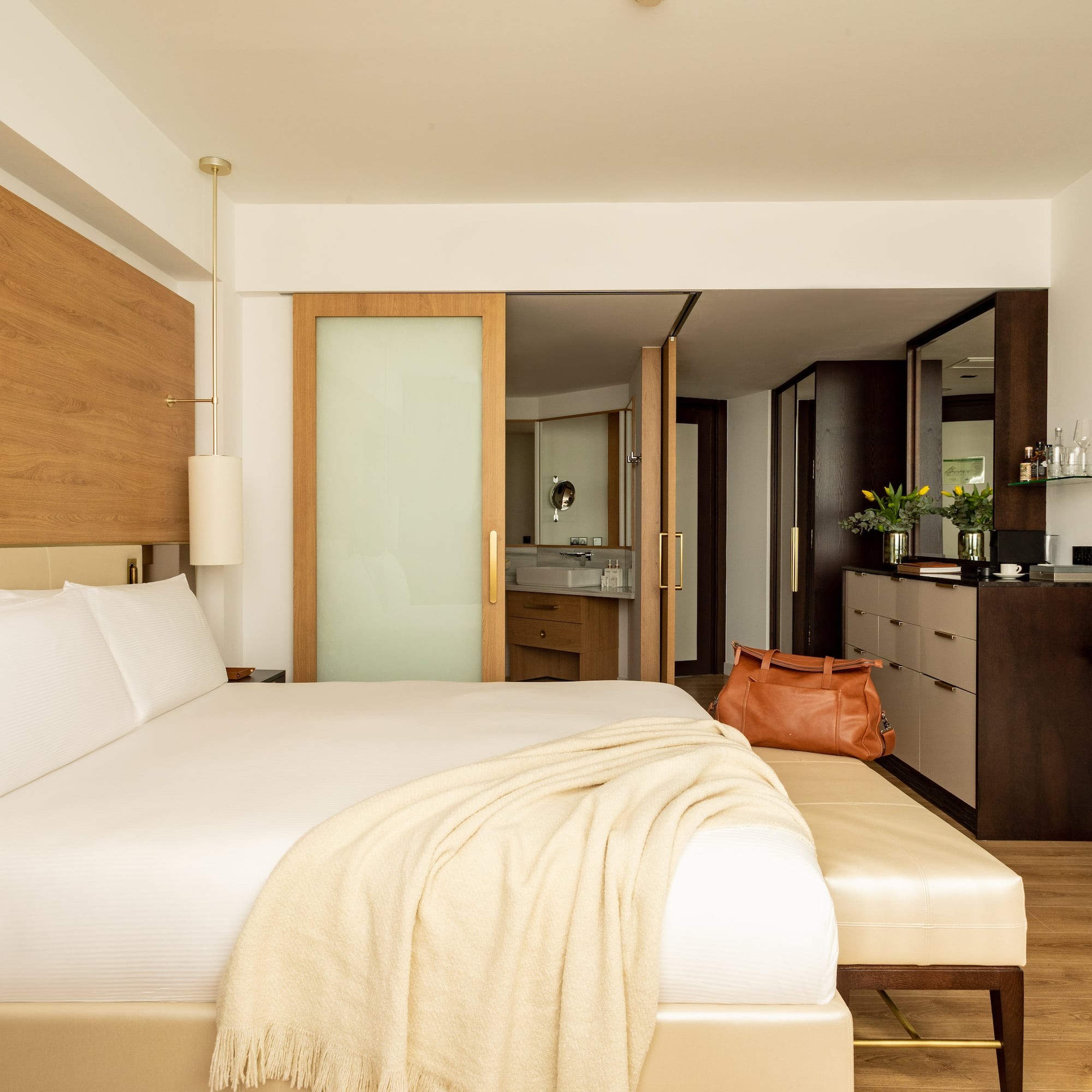 a bed with a white blanket and a brown bag in a room