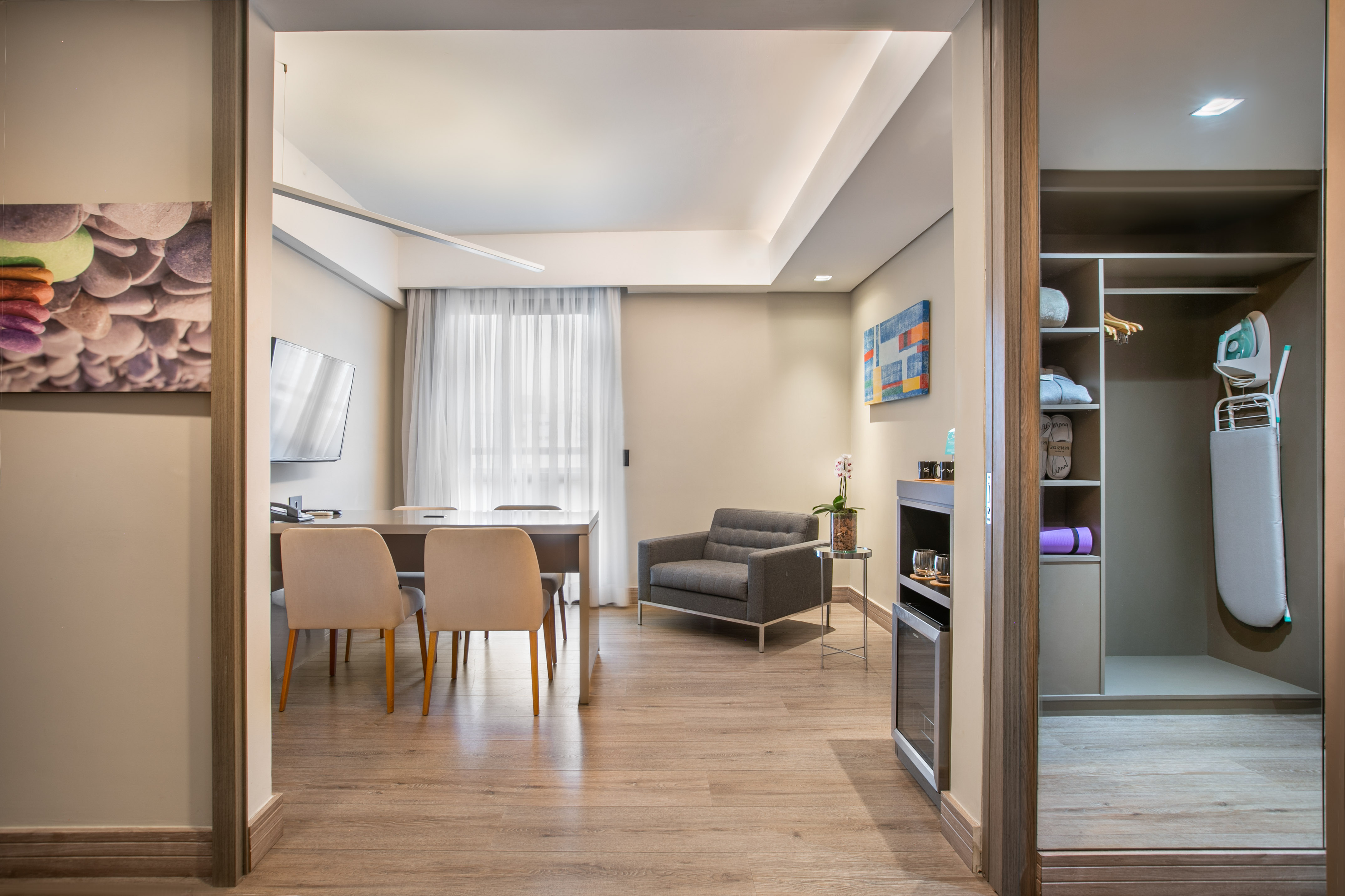 Modern hotel suite with living and dining areas, plus an open closet.