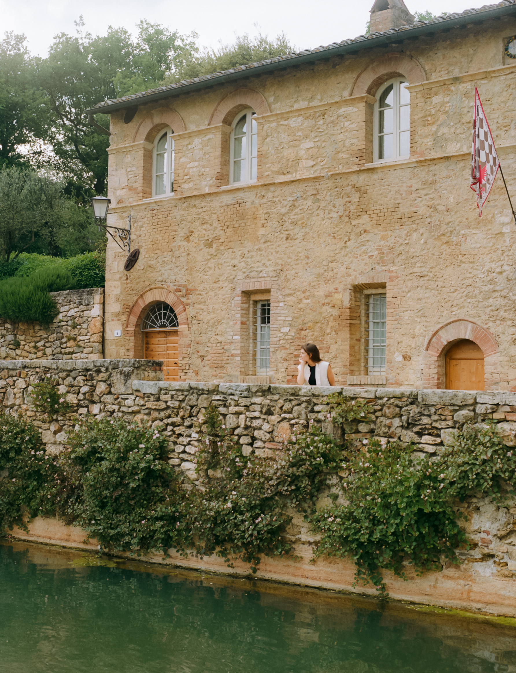 a woman standing on a stone wall next to a river