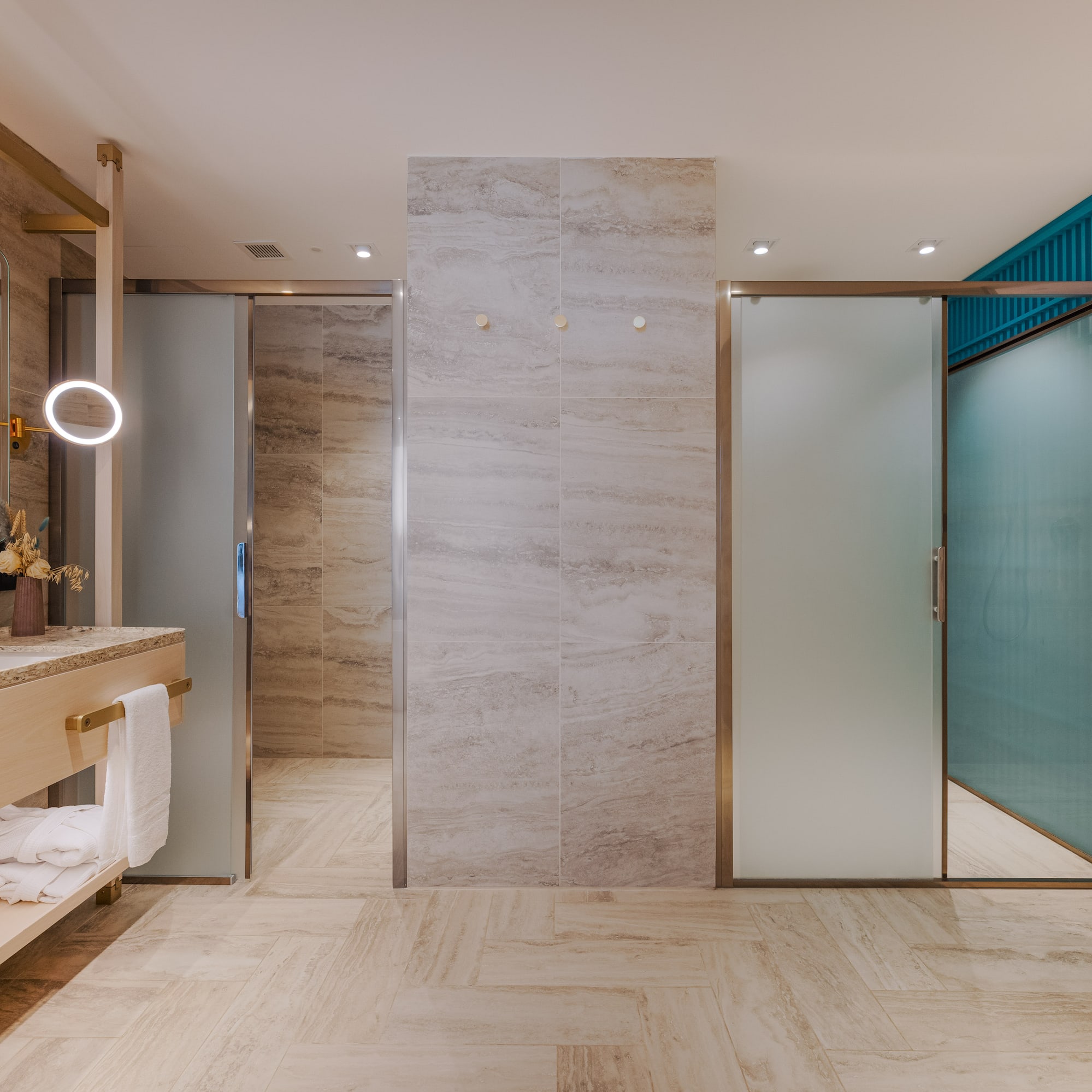 Modern bathroom with gold fixtures, LED mirror, and frosted glass doors.