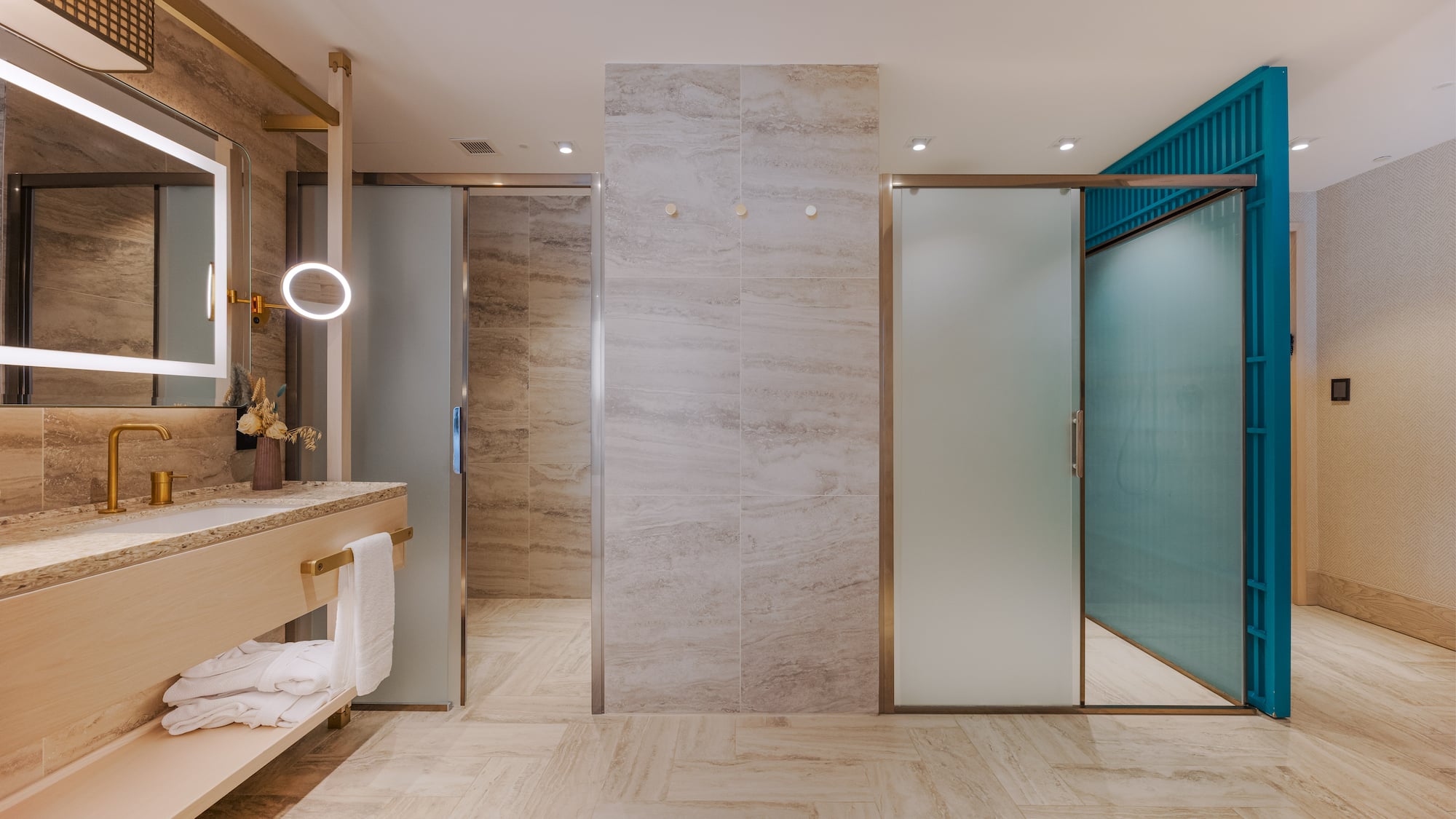 Modern bathroom with gold fixtures, LED mirror, and frosted glass doors.