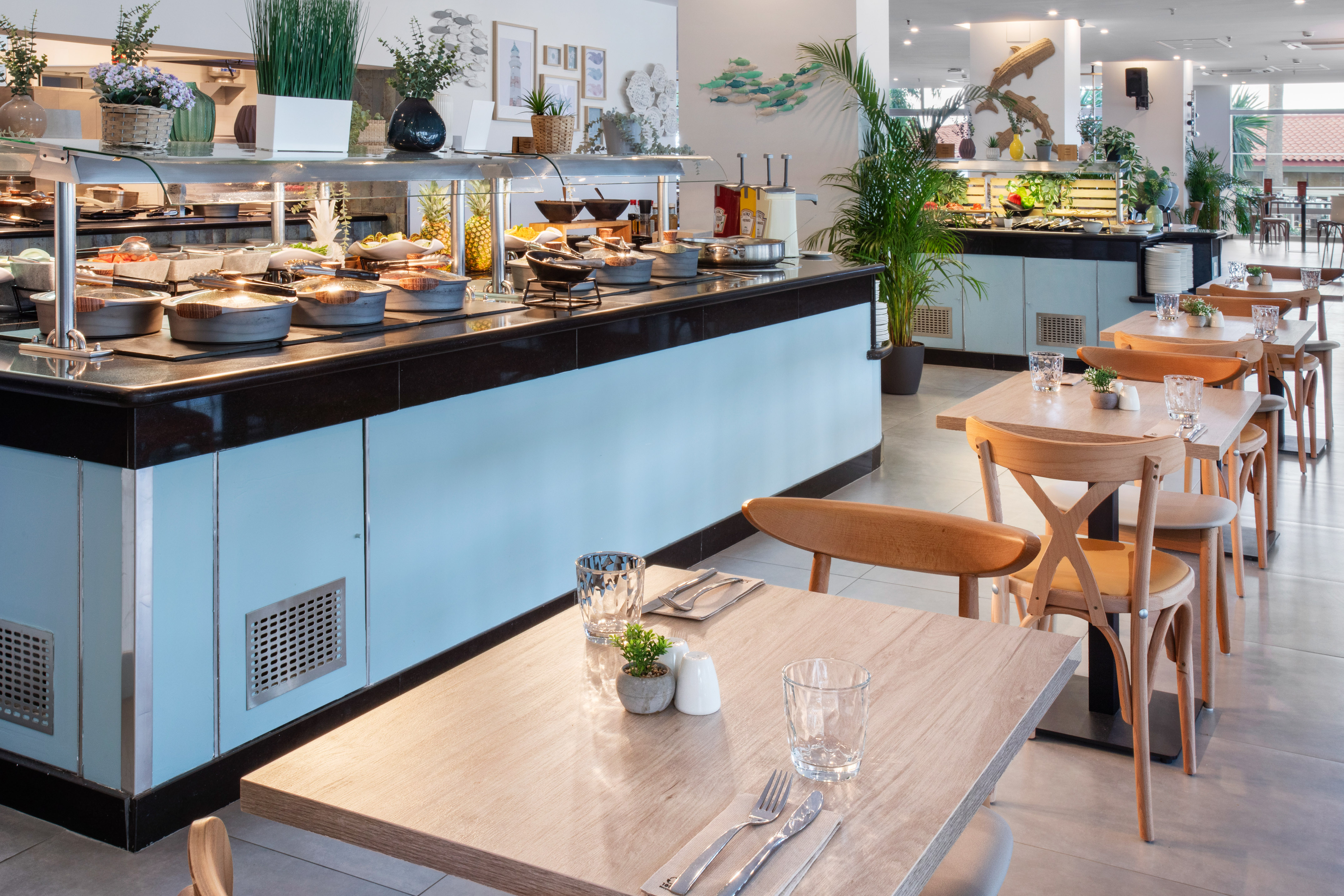 Modern hotel buffet restaurant with varied food, set tables, and bright decor.