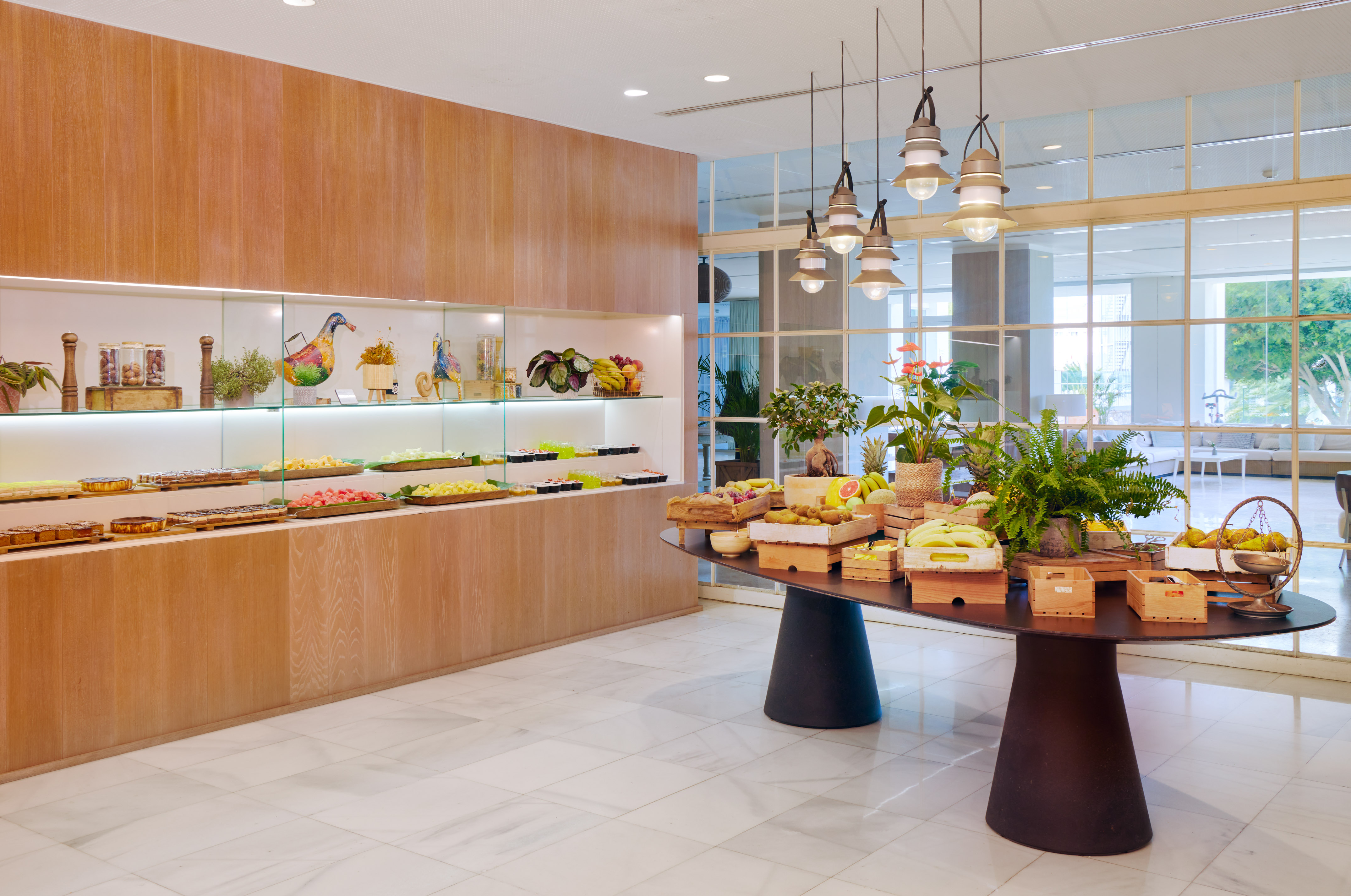 Bright hotel buffet with fresh fruit, pastries, and modern interior.