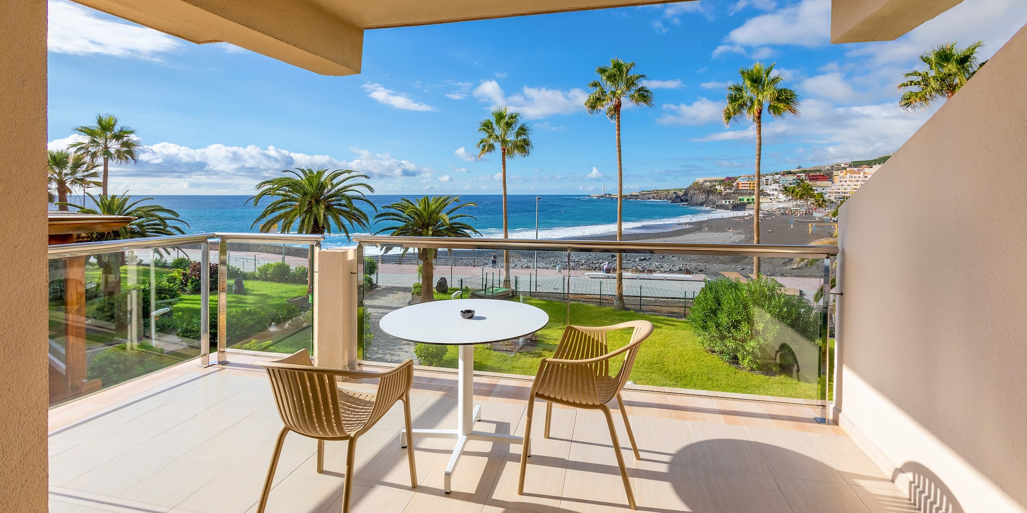a balcony with chairs and a table overlooking the ocean