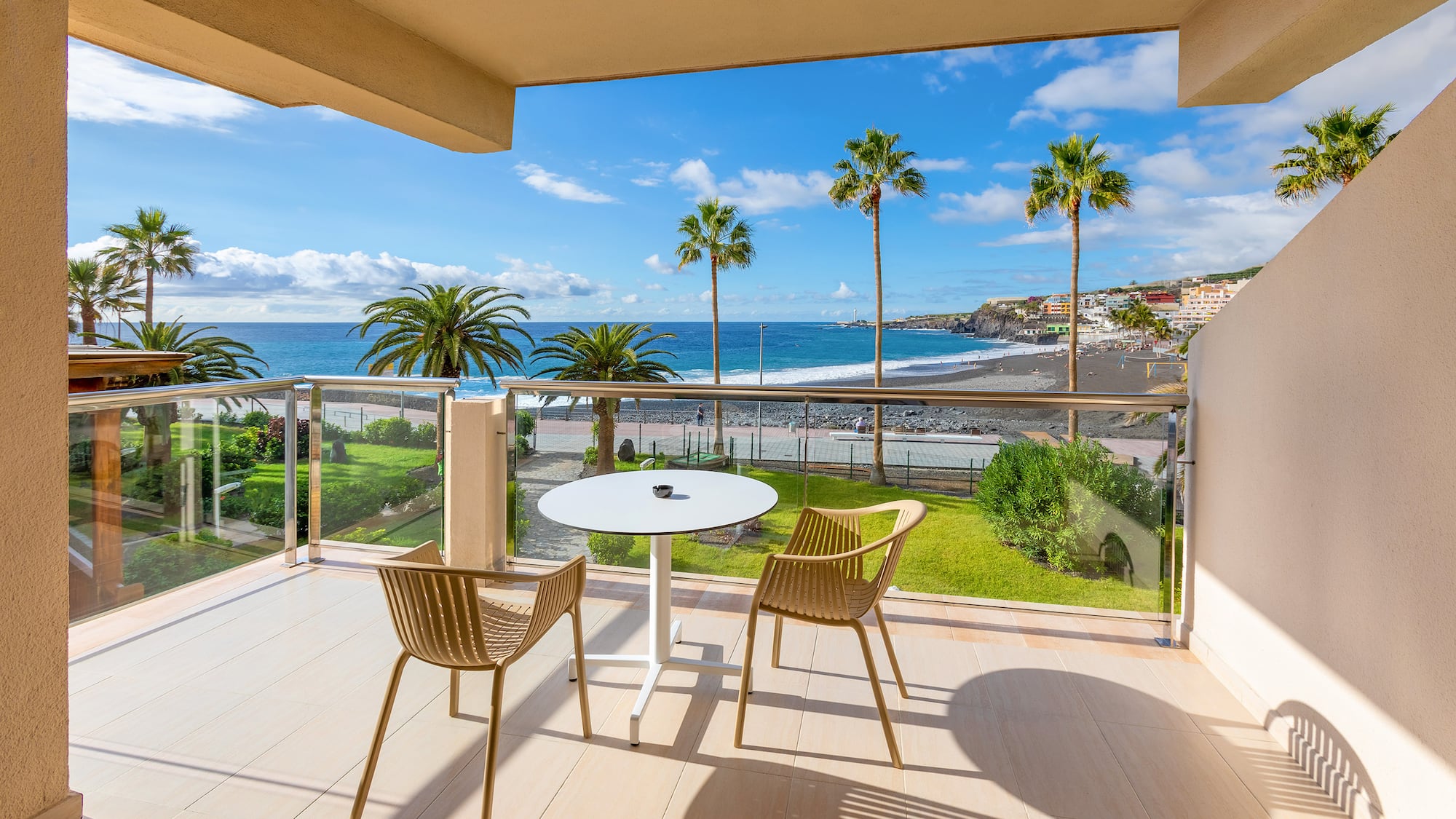a balcony with chairs and a table overlooking the ocean