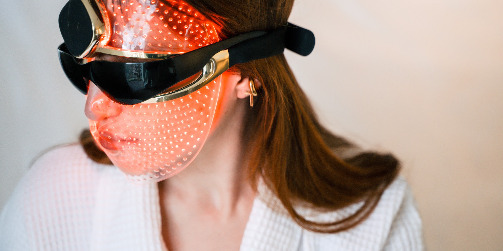 Red light therapy LED mask on woman's face for skincare.