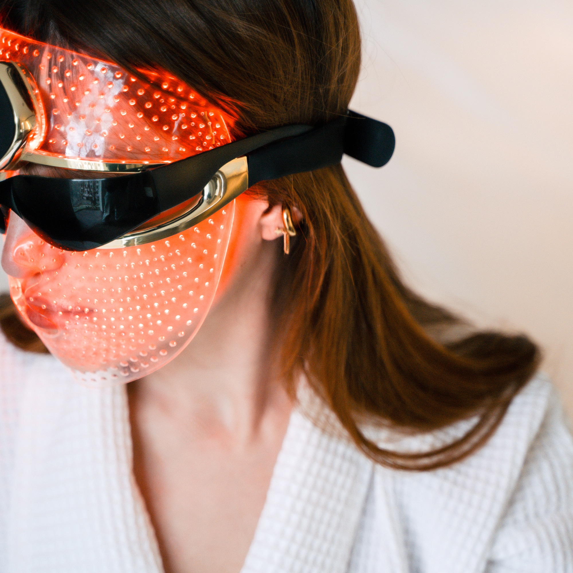 Red light therapy LED mask on woman's face for skincare.