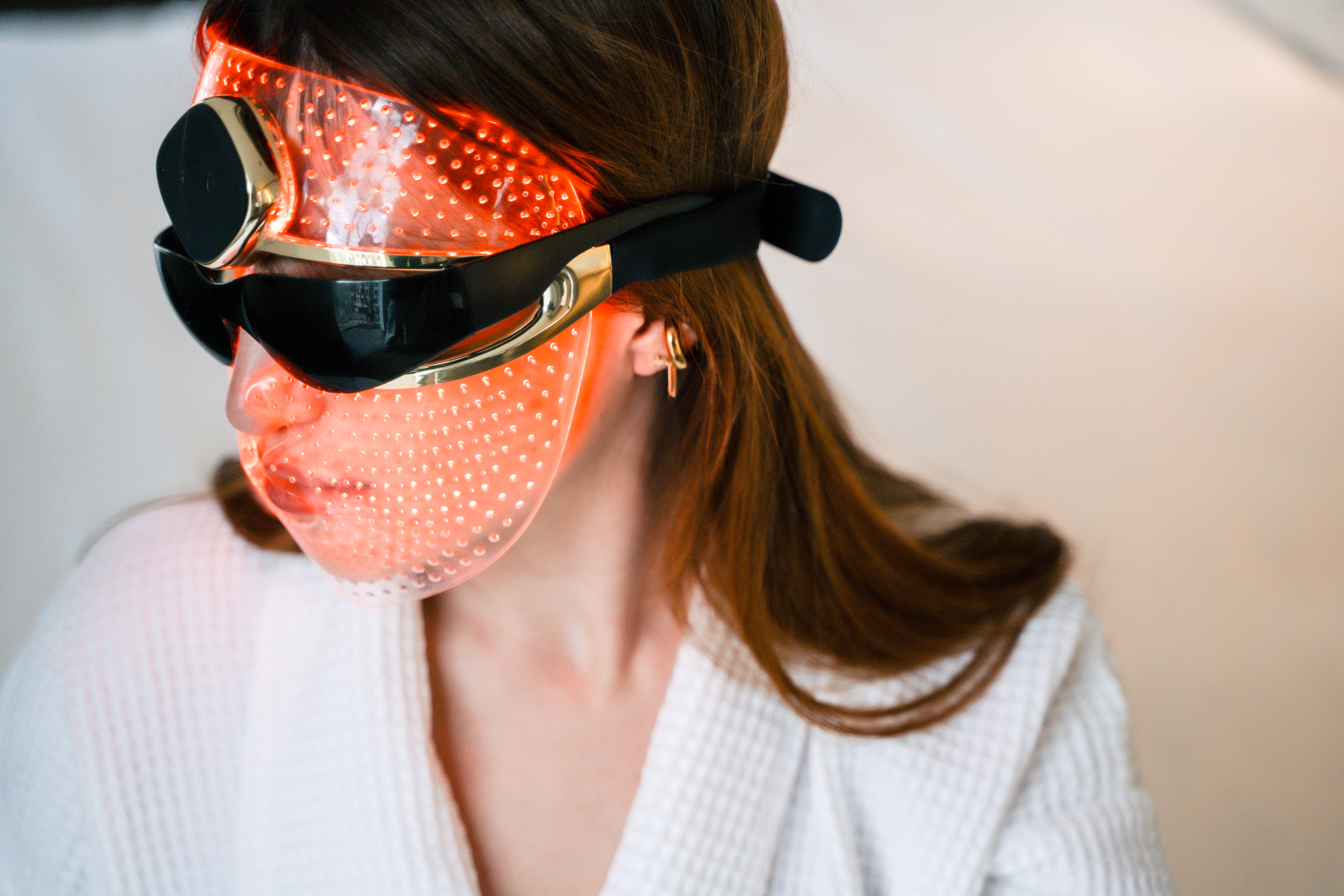 Red light therapy LED mask on woman's face for skincare.