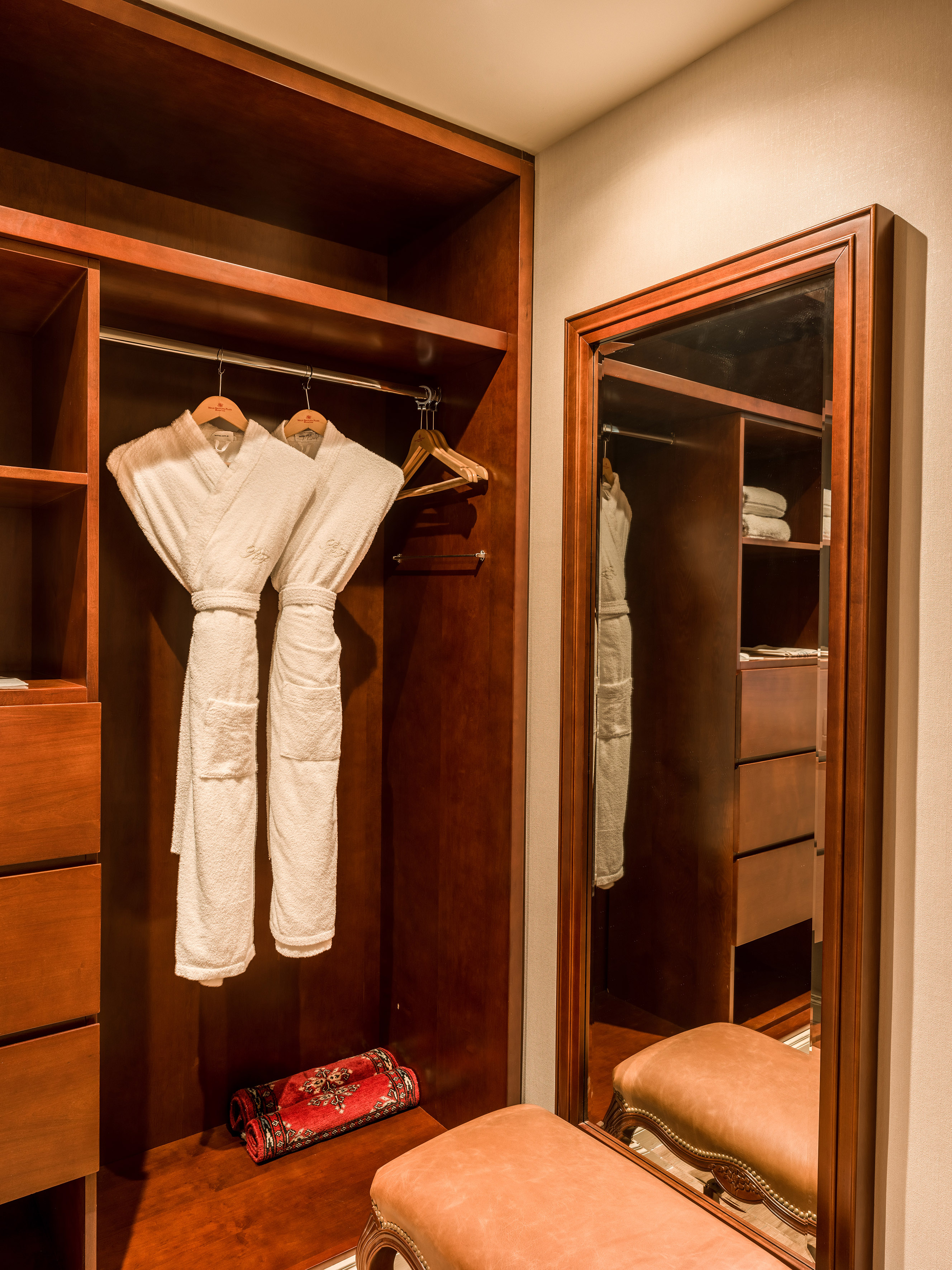 Hotel walk-in closet with hanging bathrobes, mirror, and ottoman. - Junior Suite - Melia Recoleta Plaza, Buenos Aires