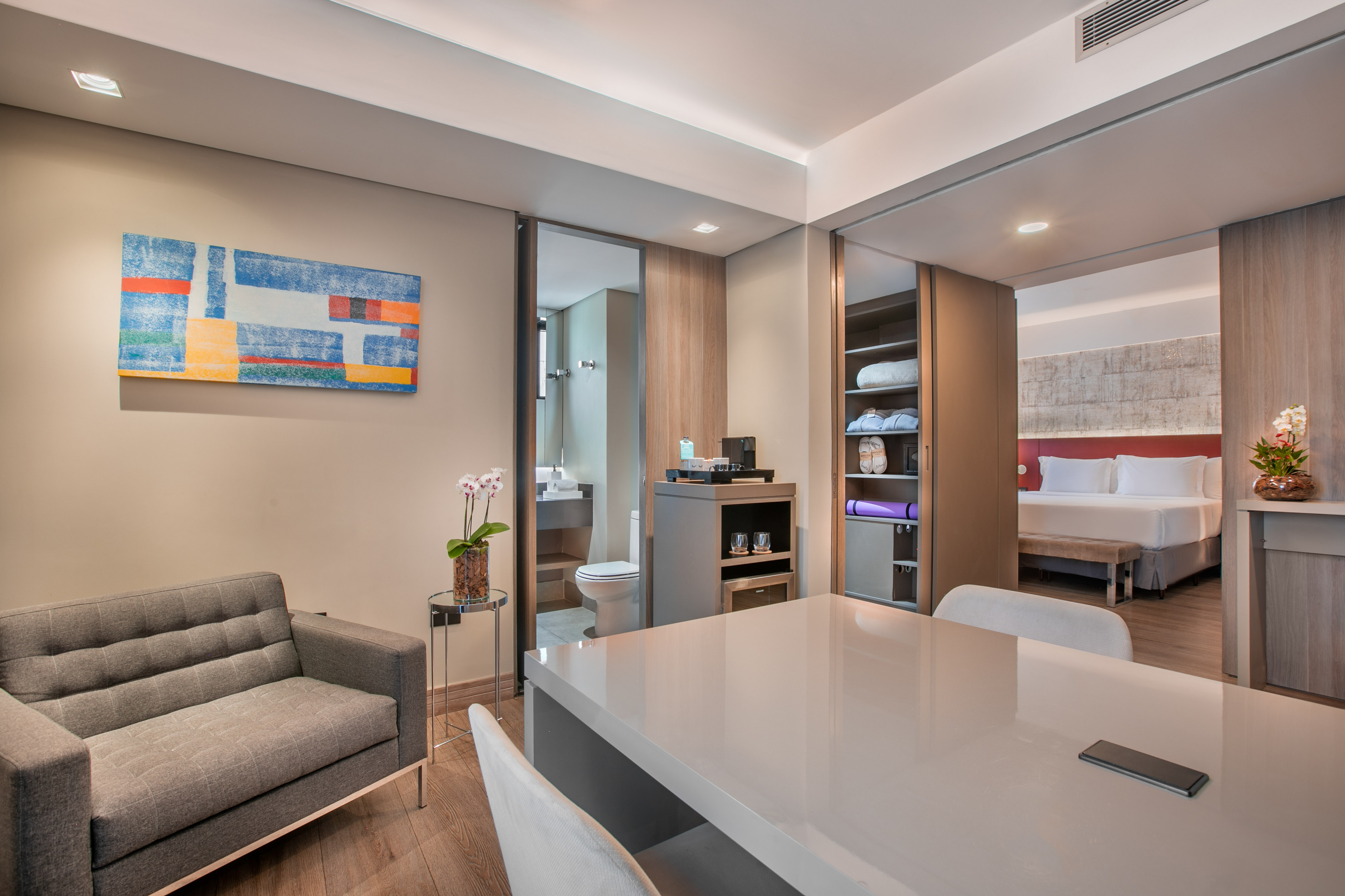 Contemporary hotel suite with open living, dining, and bedroom areas.