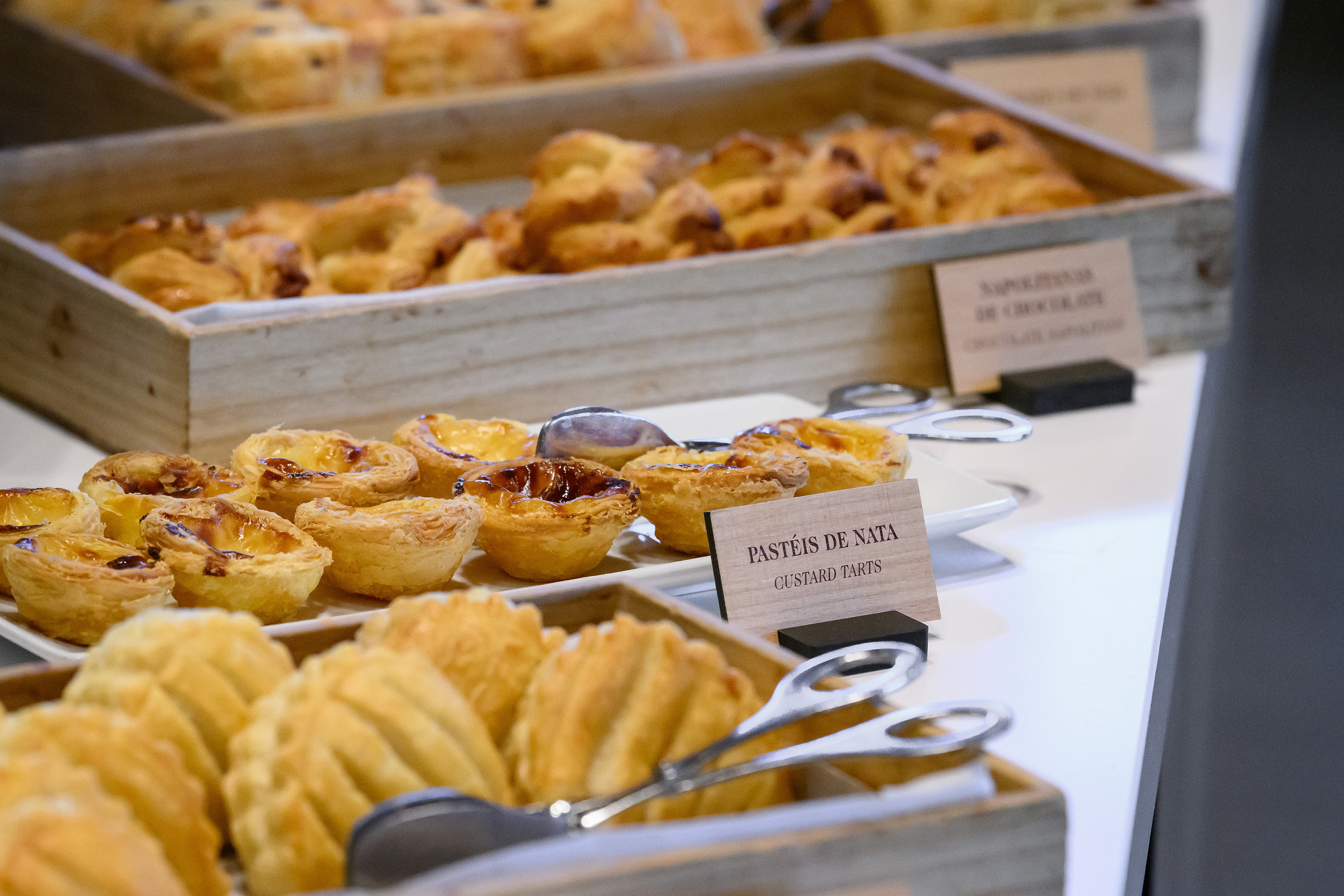 Golden Pastéis de Nata custard tarts and assorted pastries at a buffet.