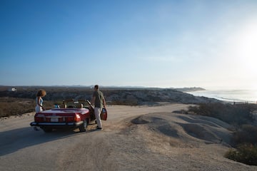 a man standing next to a red convertible car