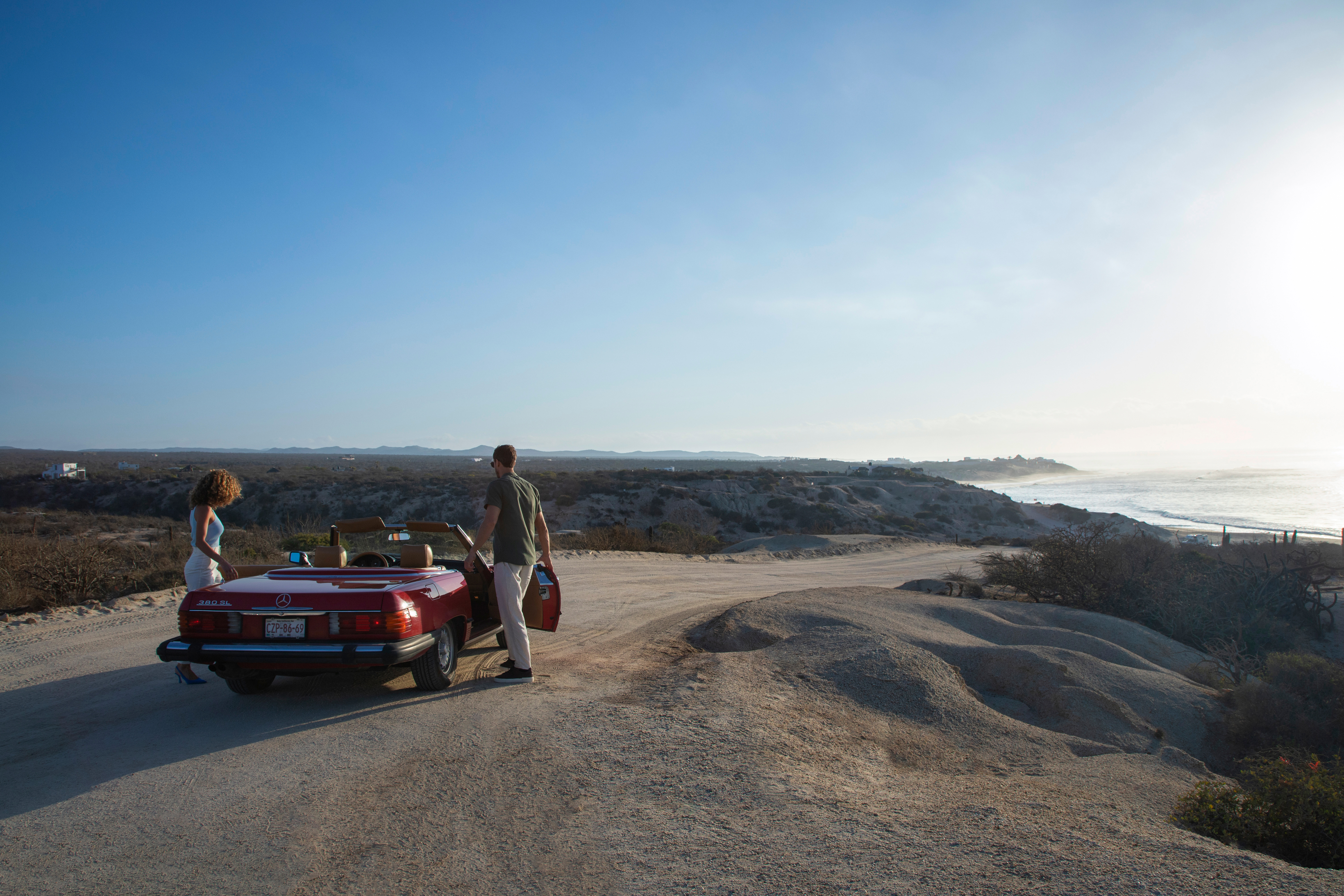 a man standing next to a red convertible car