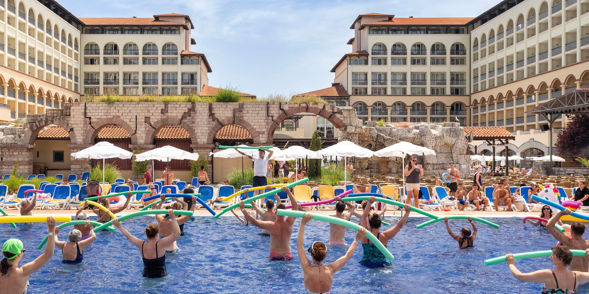 a group of people in a pool with noodle sticks