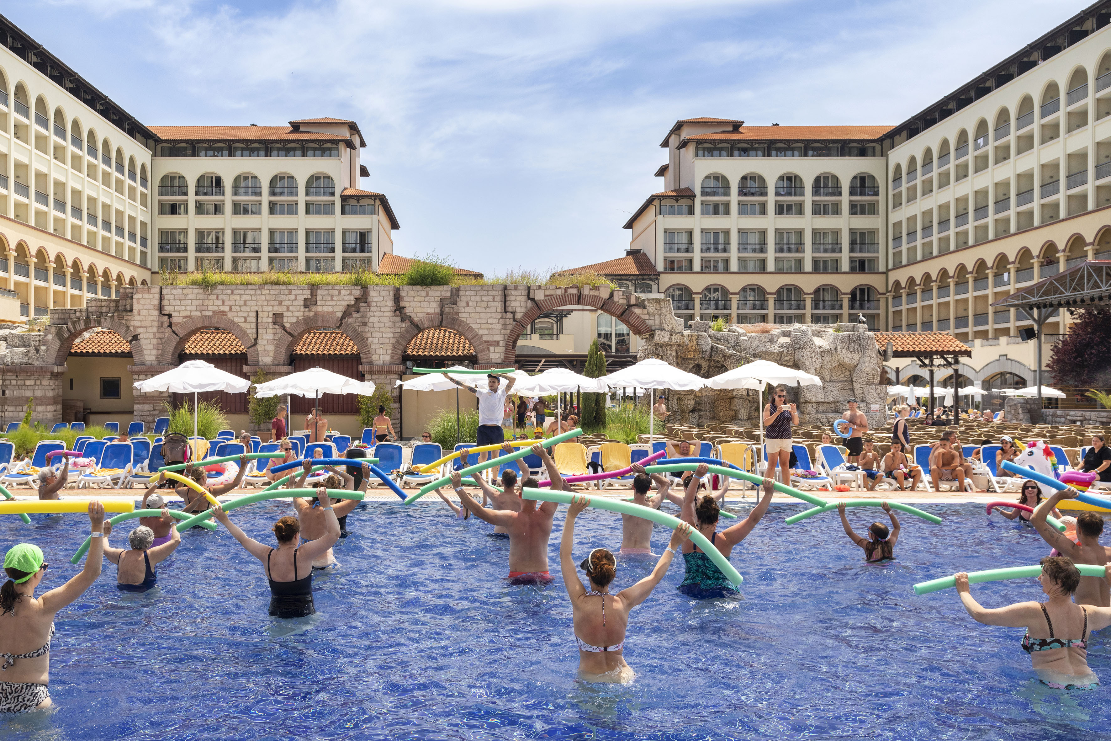 a group of people in a pool with noodle sticks