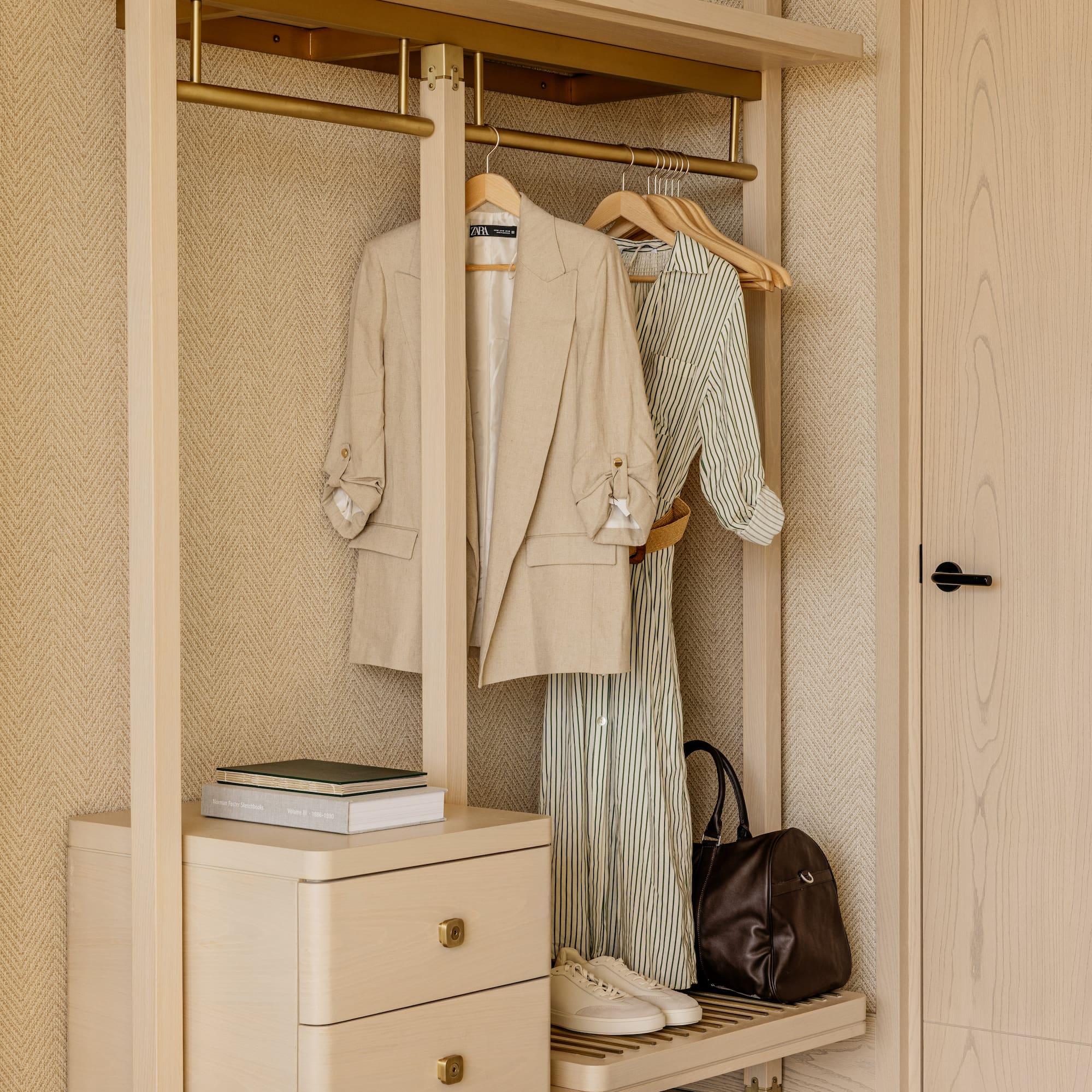 a closet with clothes on swingers and a dresser