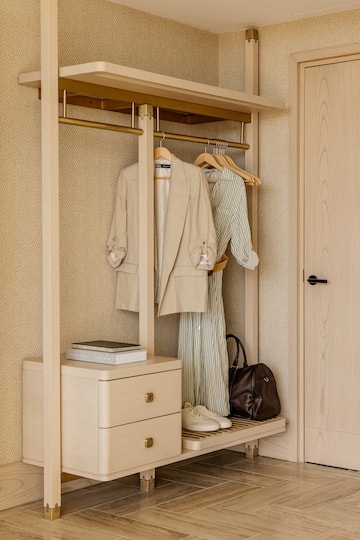 a closet with clothes on swingers and a dresser