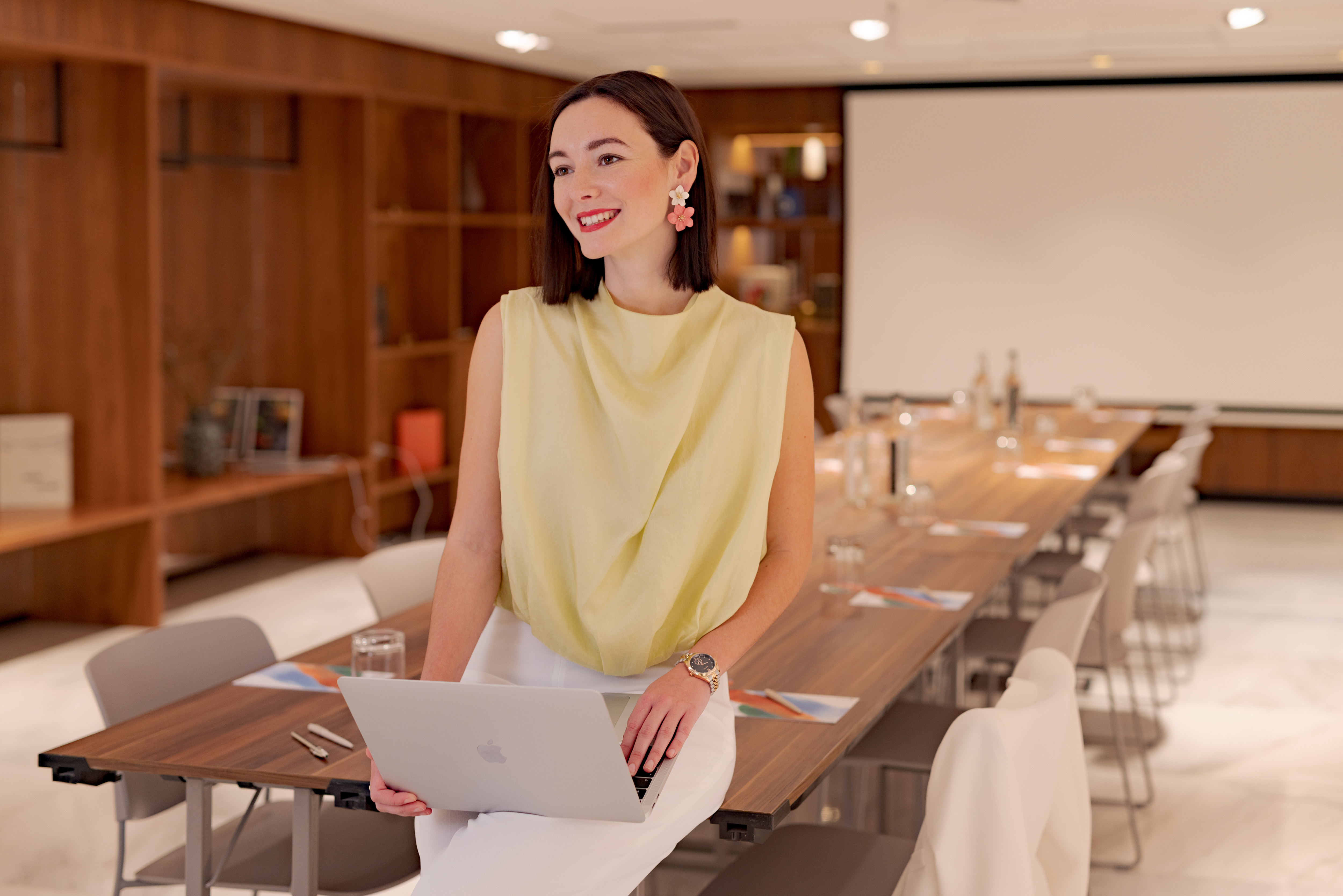 a woman sitting at a long table with a laptop