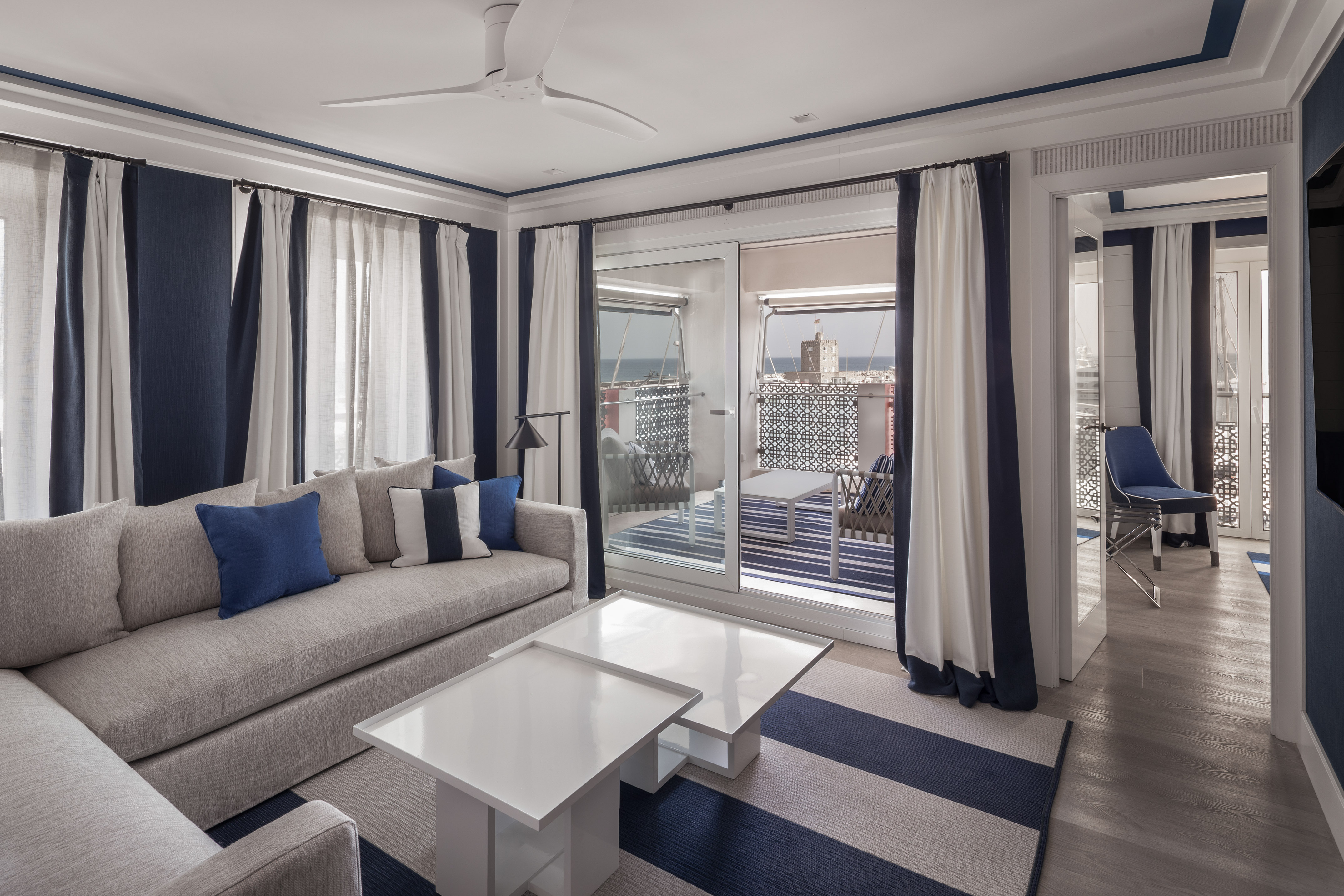 Coastal living room suite with blue/white decor, sofa, and ocean view balcony.