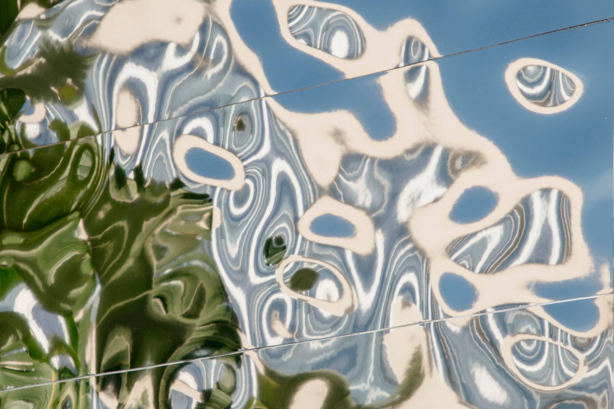Wavy green and blue reflections on a metallic surface with horizontal seams.