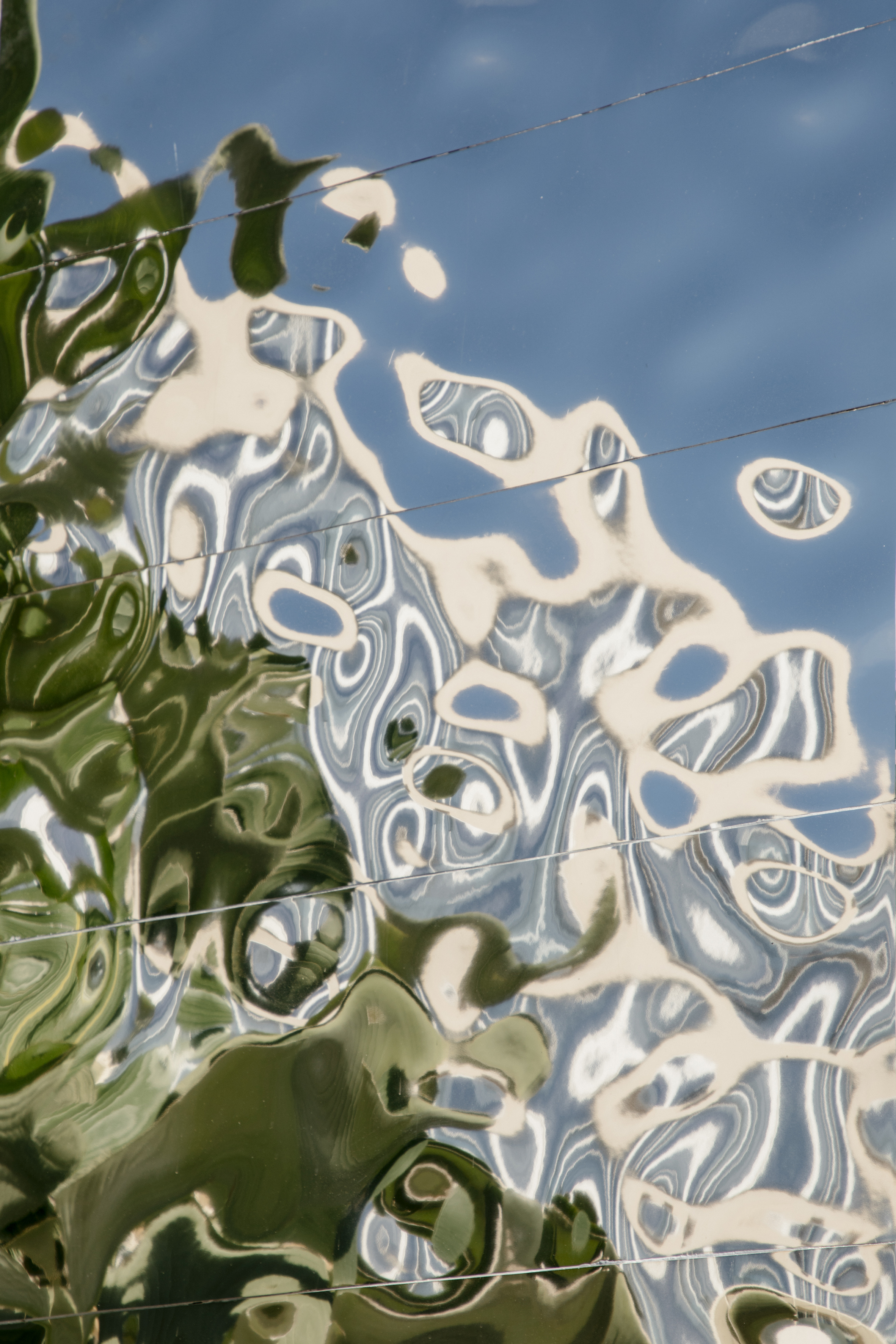 Wavy green and blue reflections on a metallic surface with horizontal seams.