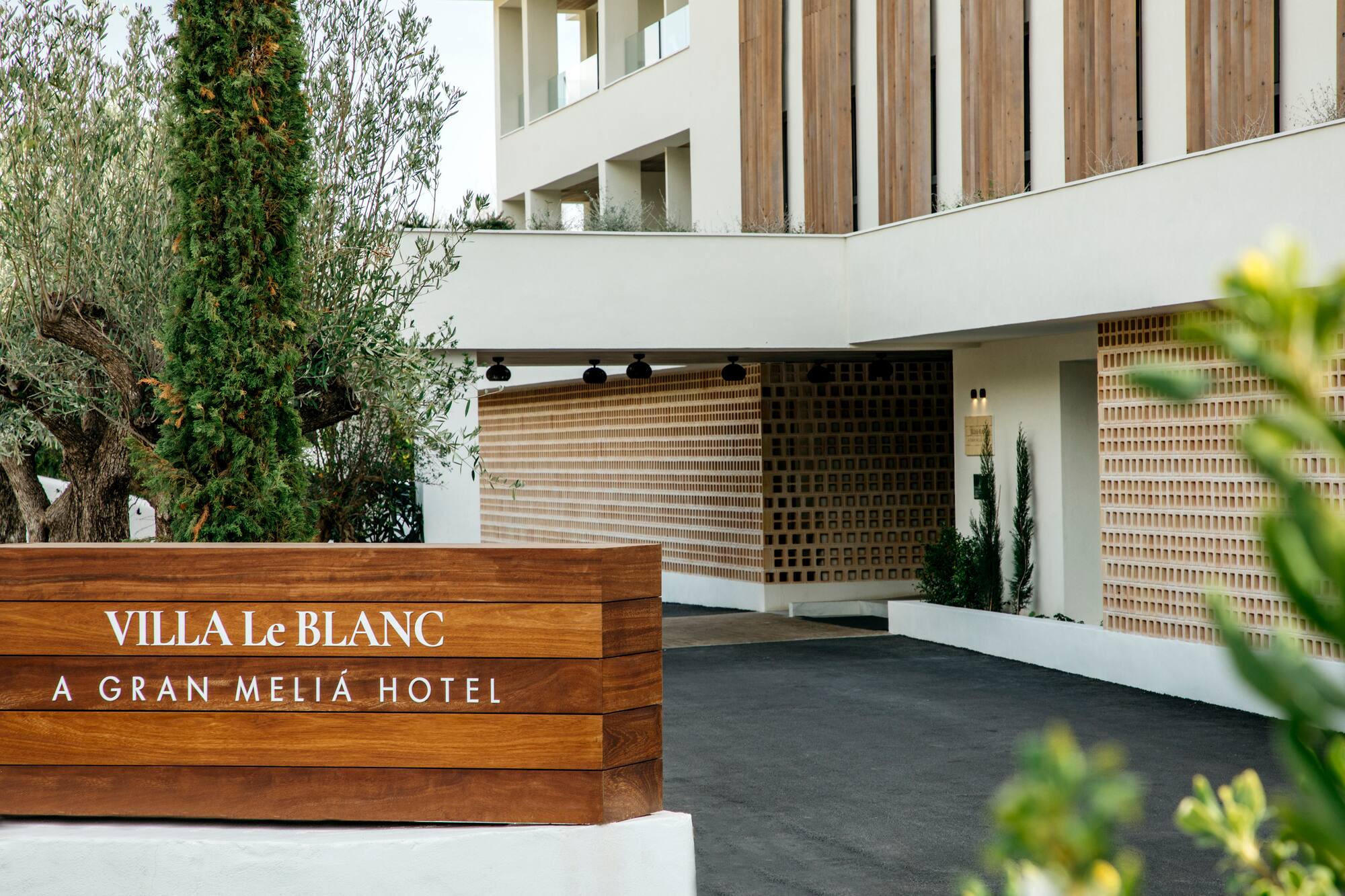 Villa Le Blanc Gran Meliá Hotel entrance, modern architecture, lush trees.