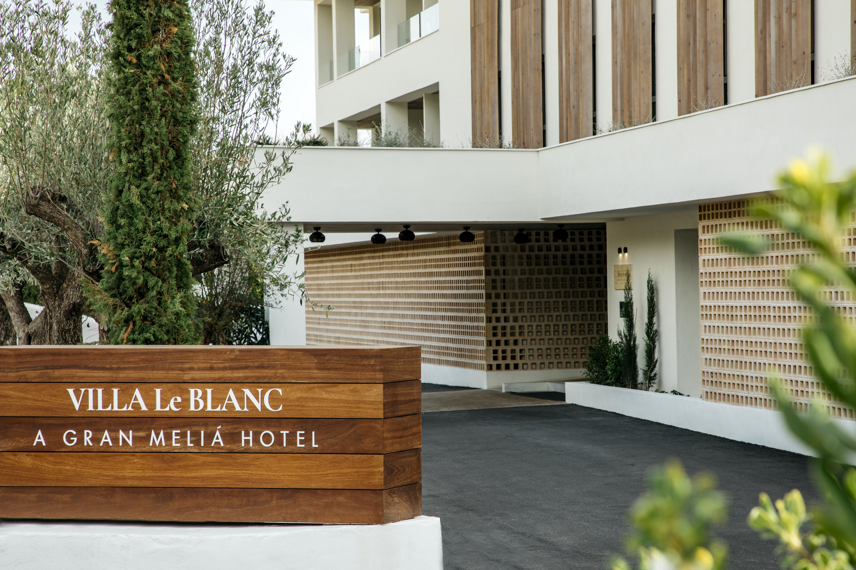 Villa Le Blanc Gran Meliá Hotel entrance, modern architecture, lush trees.