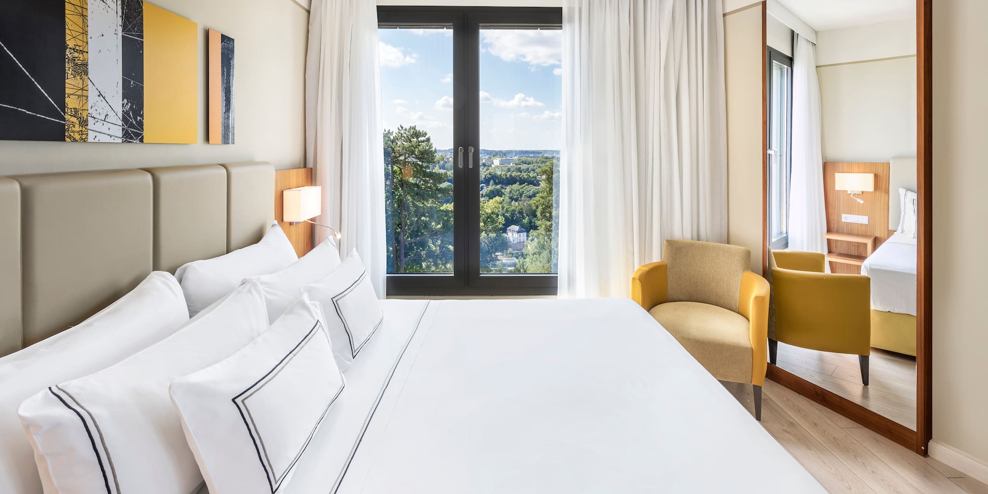 a bed with white sheets and a chair in a room with a view of the city