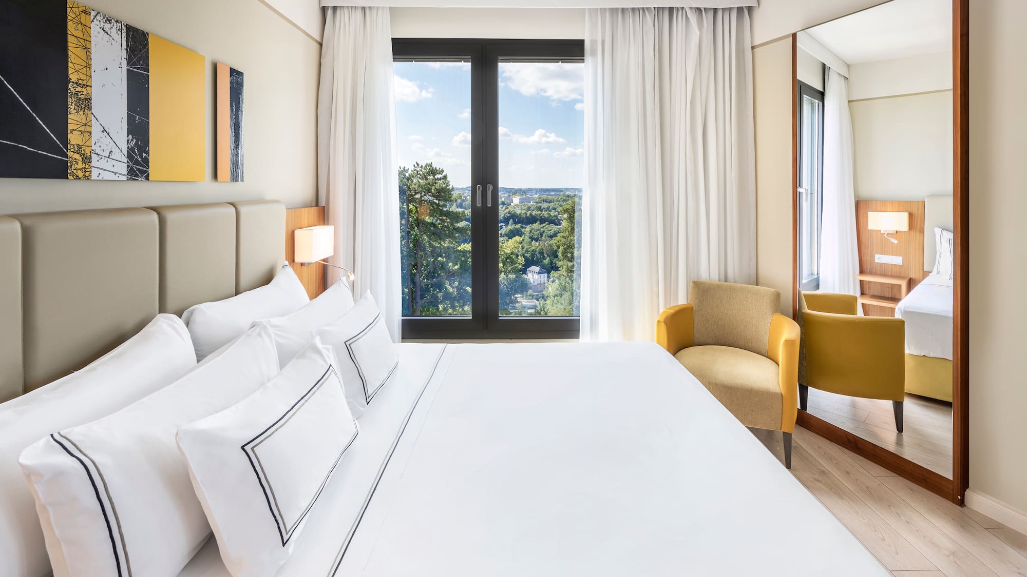 a bed with white sheets and a chair in a room with a view of the city