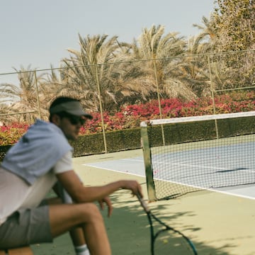 a man sitting on a bench with a tennis racket