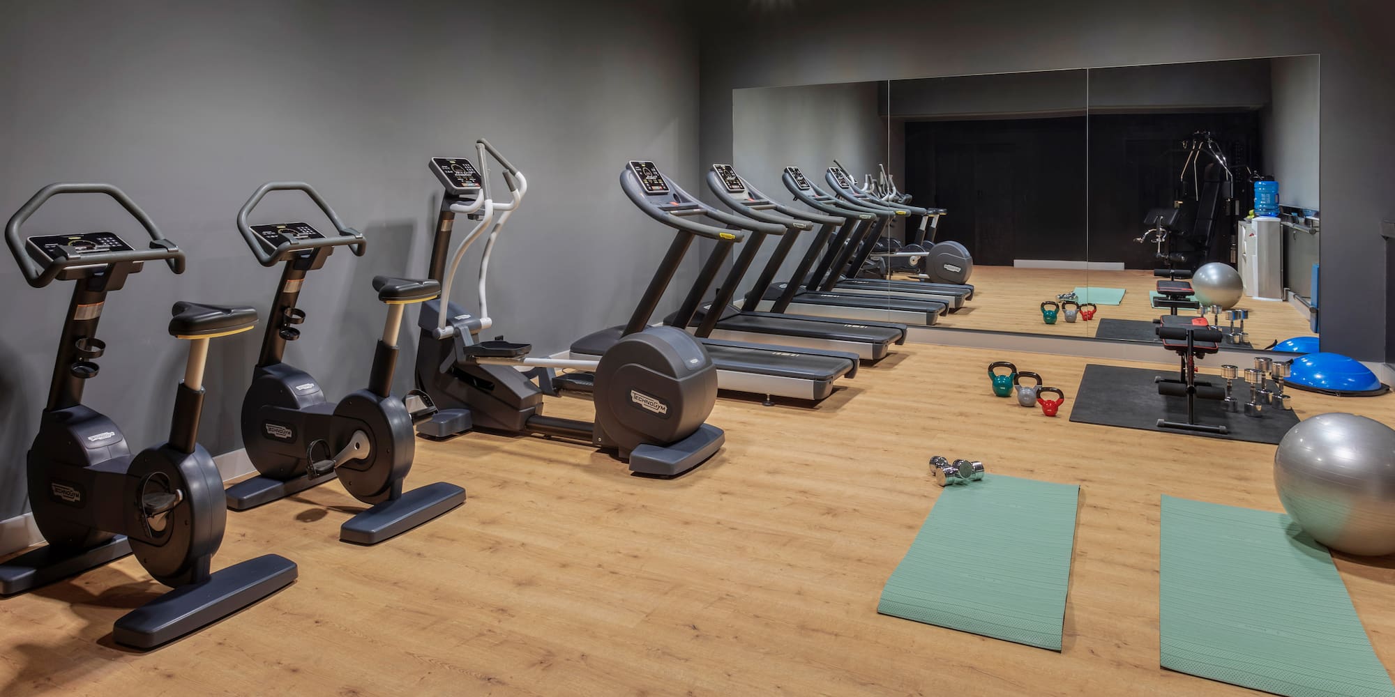 Gimnasio de hotel moderno con máquinas de cardio y pesas.