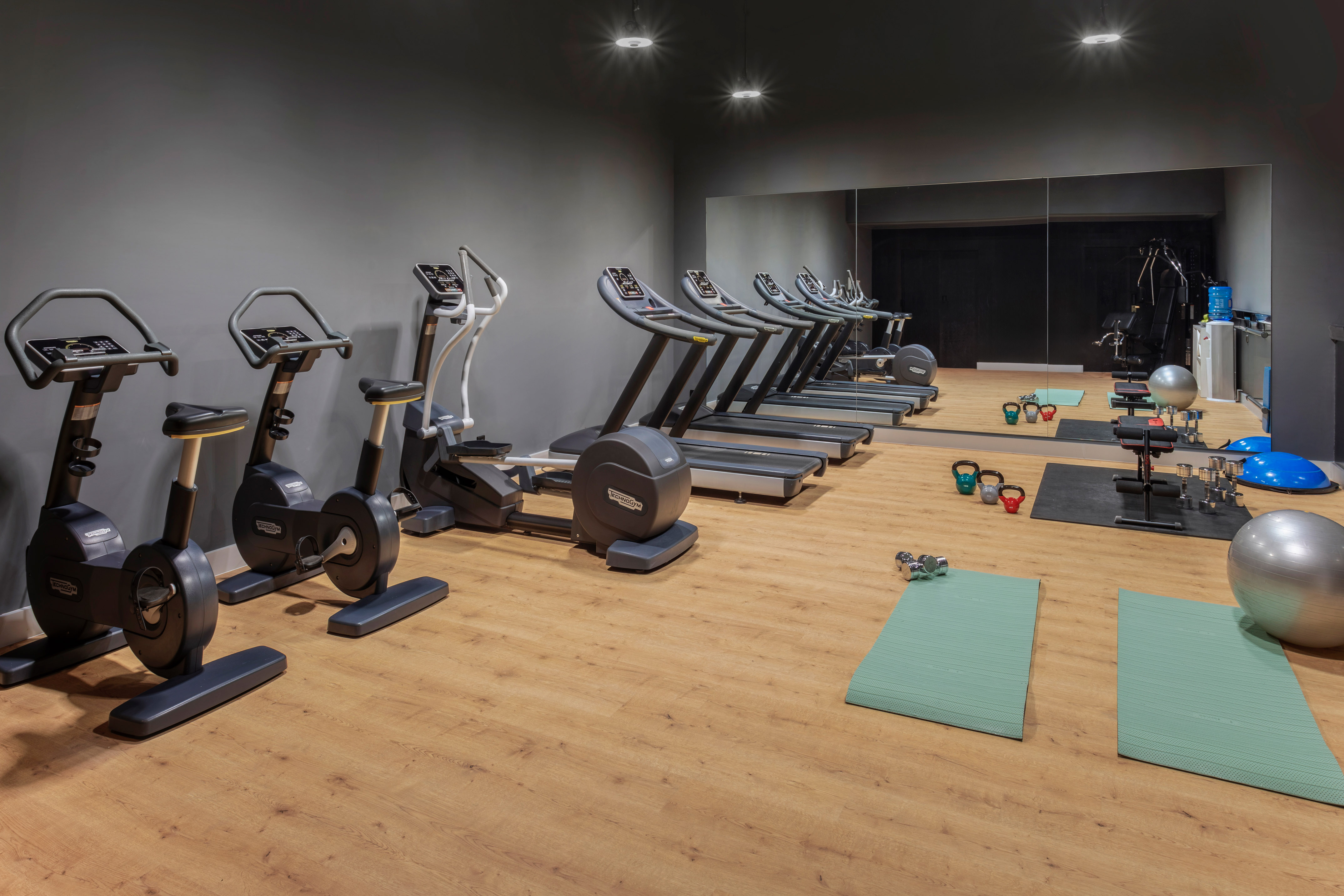 Moderno gimnasio con cintas de correr, bicicletas, pesas y colchonetas