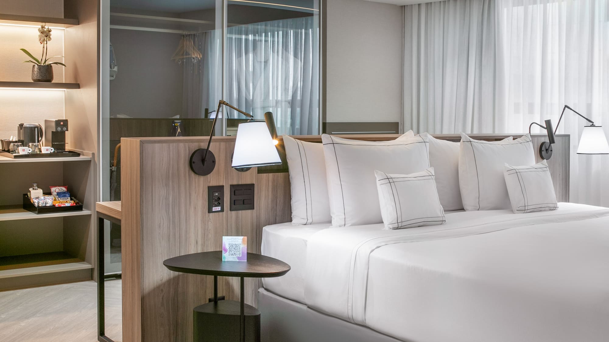 a bed with white sheets and a table with lamps