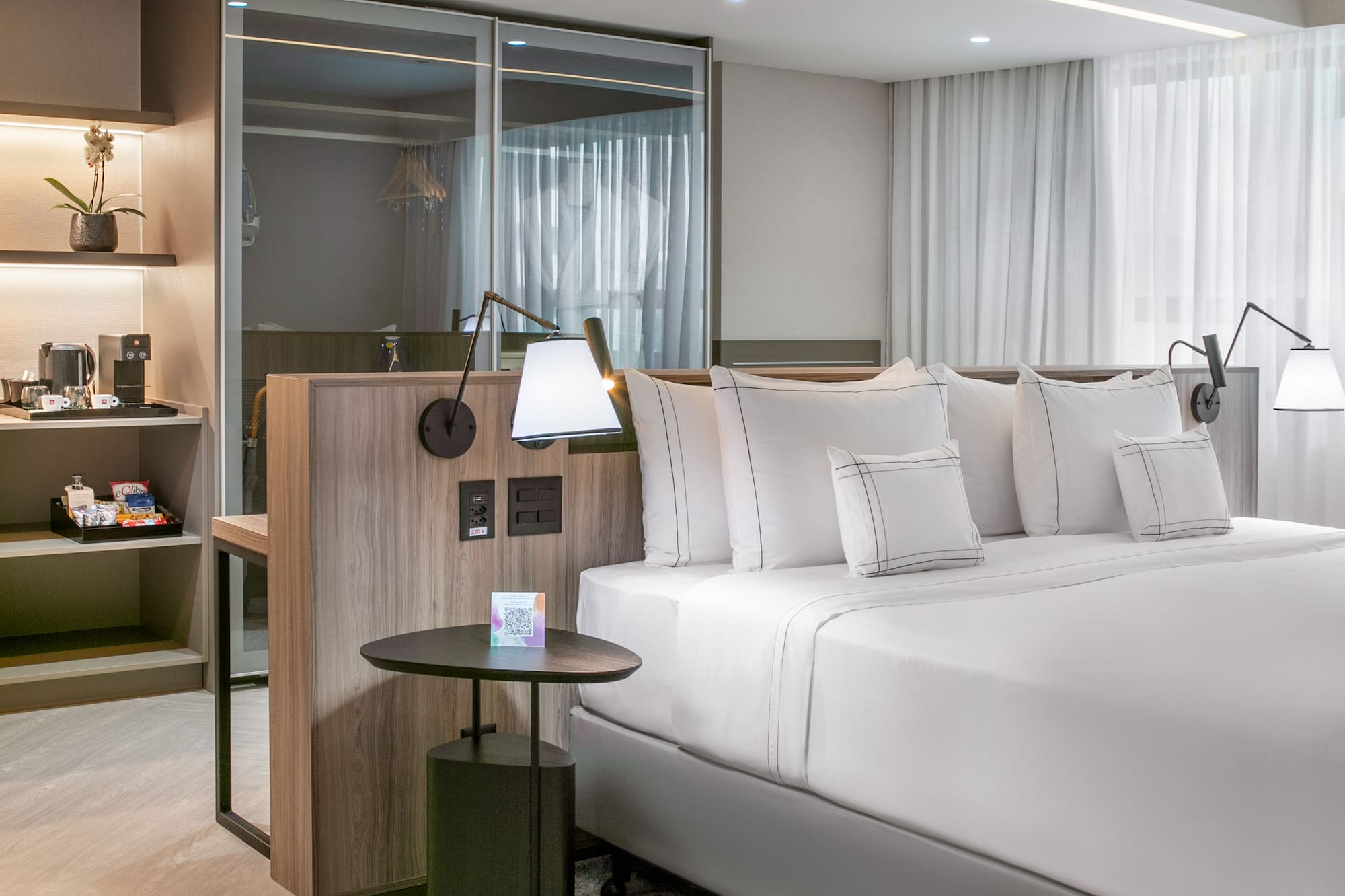 a bed with white sheets and a table with lamps