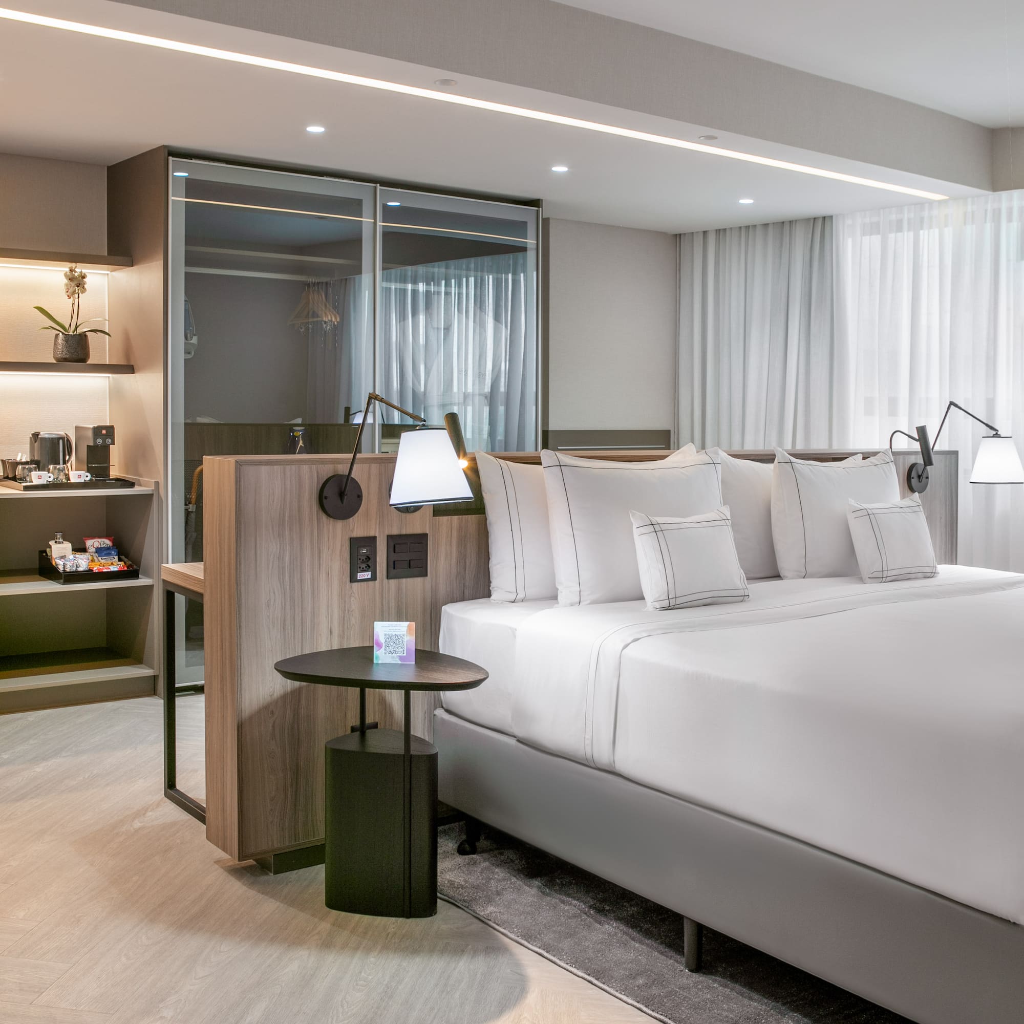 a bed with white sheets and a table with lamps