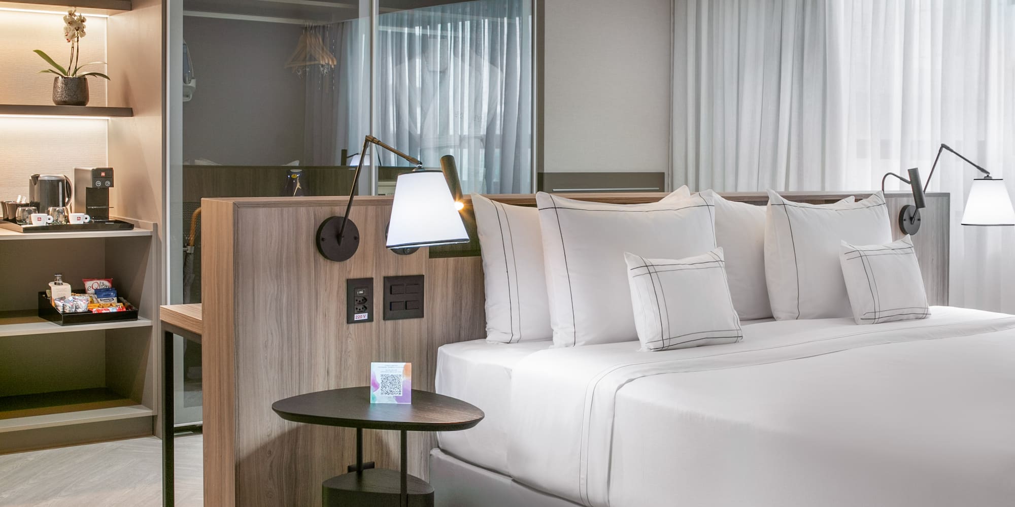 a bed with white sheets and a table with lamps