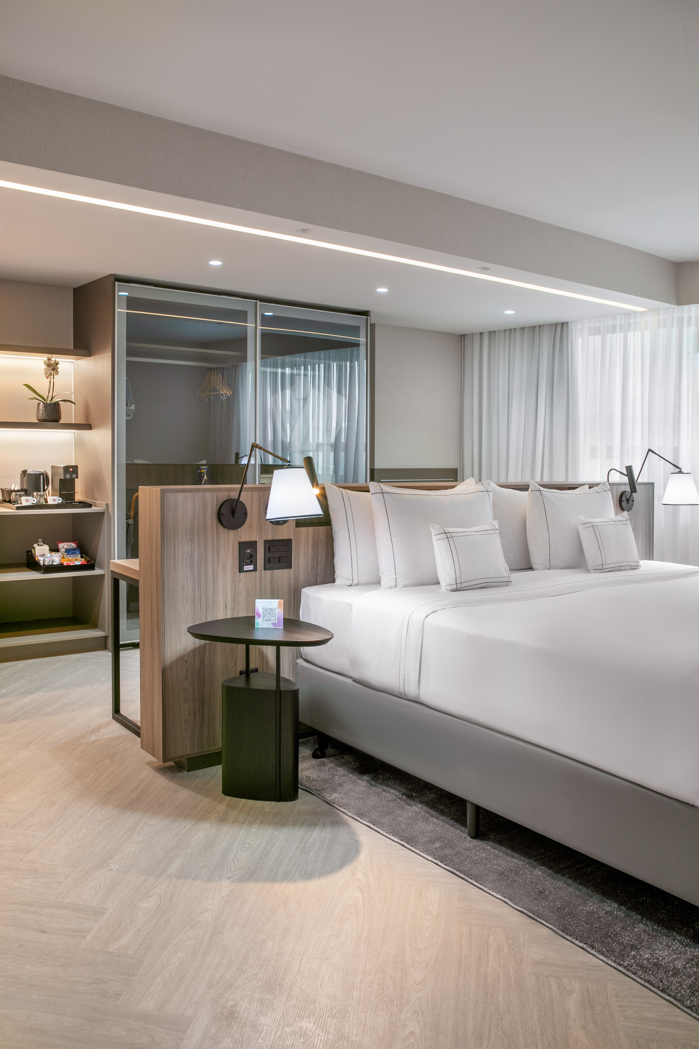 a bed with white sheets and a table with lamps