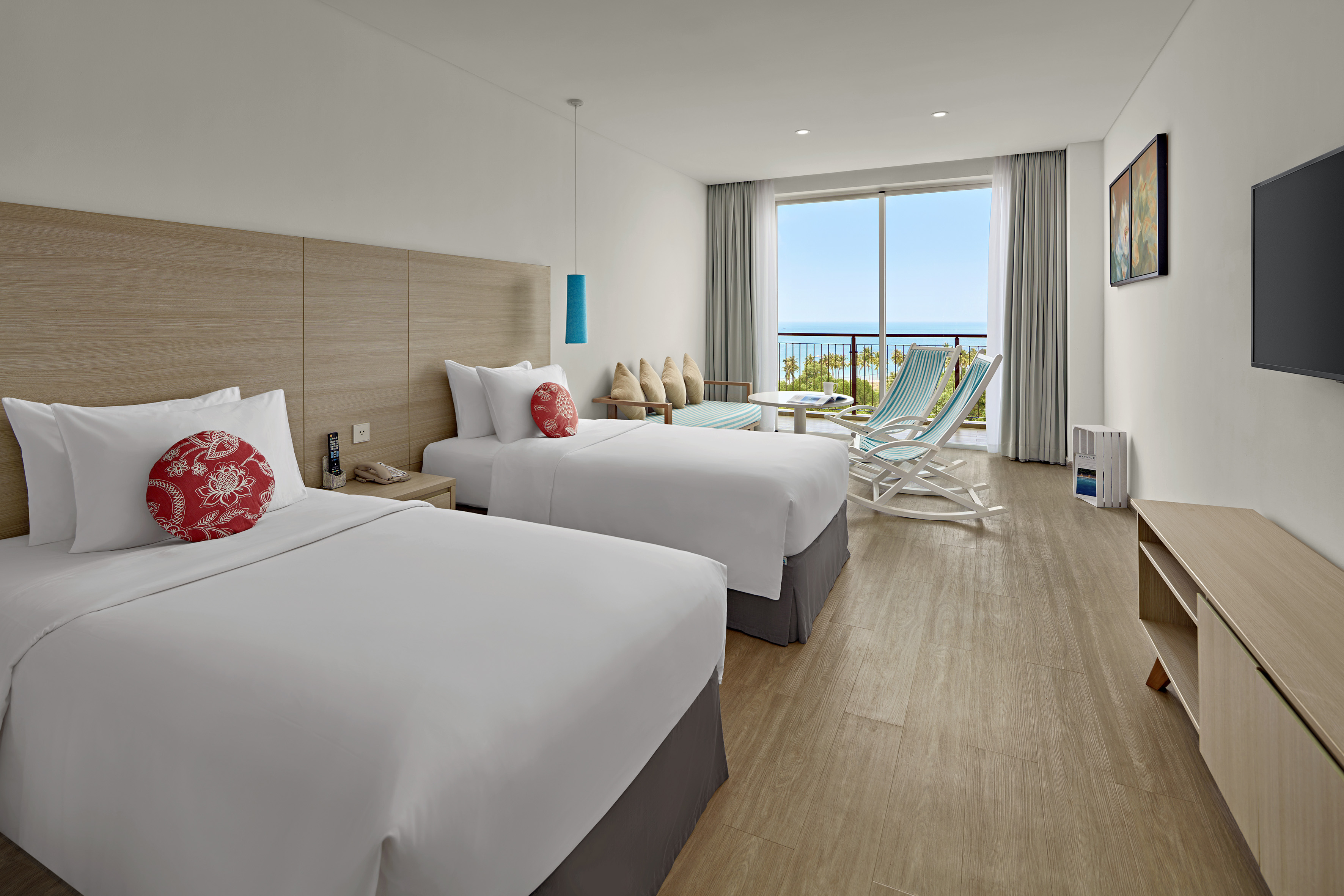 Bright resort room with twin beds and ocean view balcony.