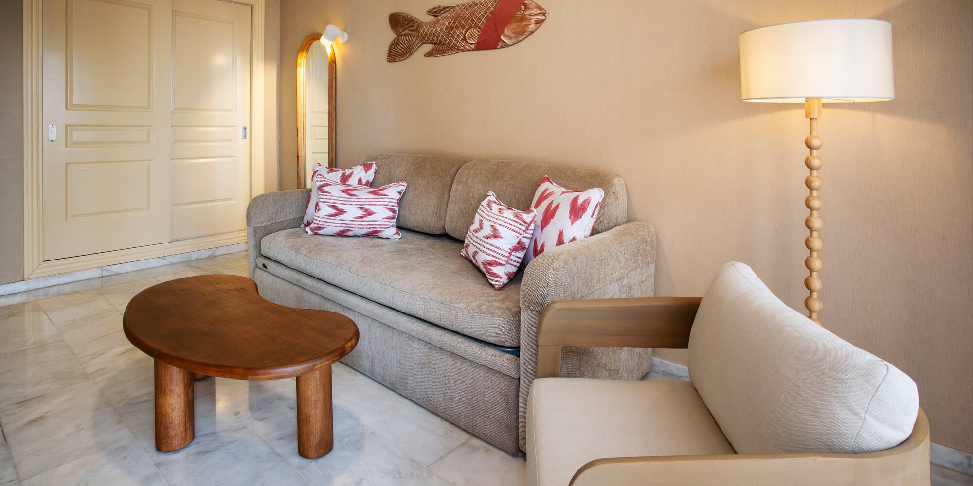 Cozy living room with beige sofa, wood table, armchair, and fish art.
