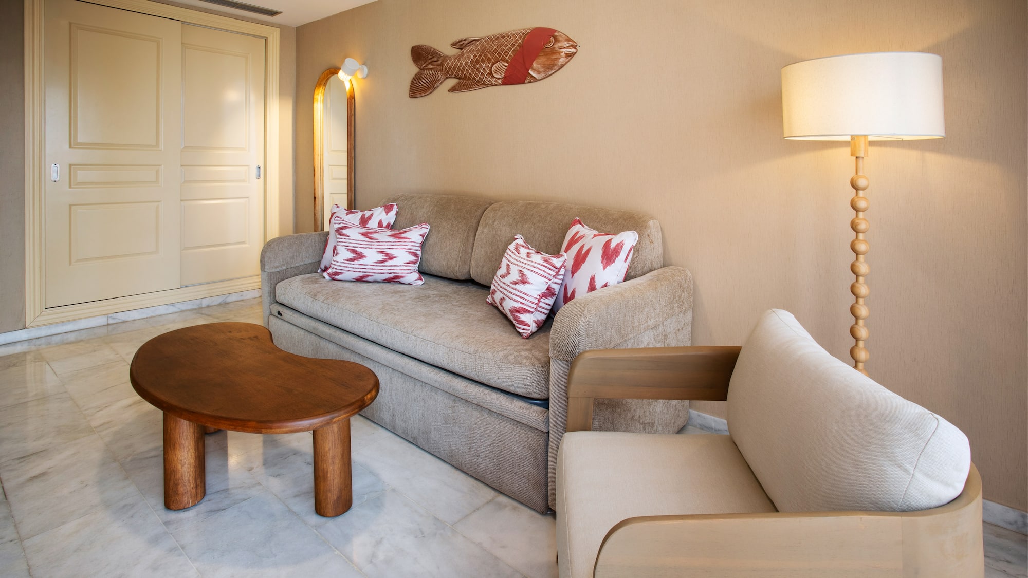 Cozy living room with beige sofa, wood table, armchair, and fish art.
