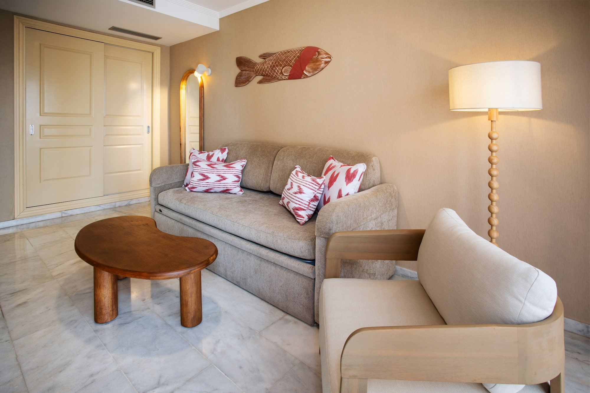 Cozy living room with beige sofa, wood table, armchair, and fish art.